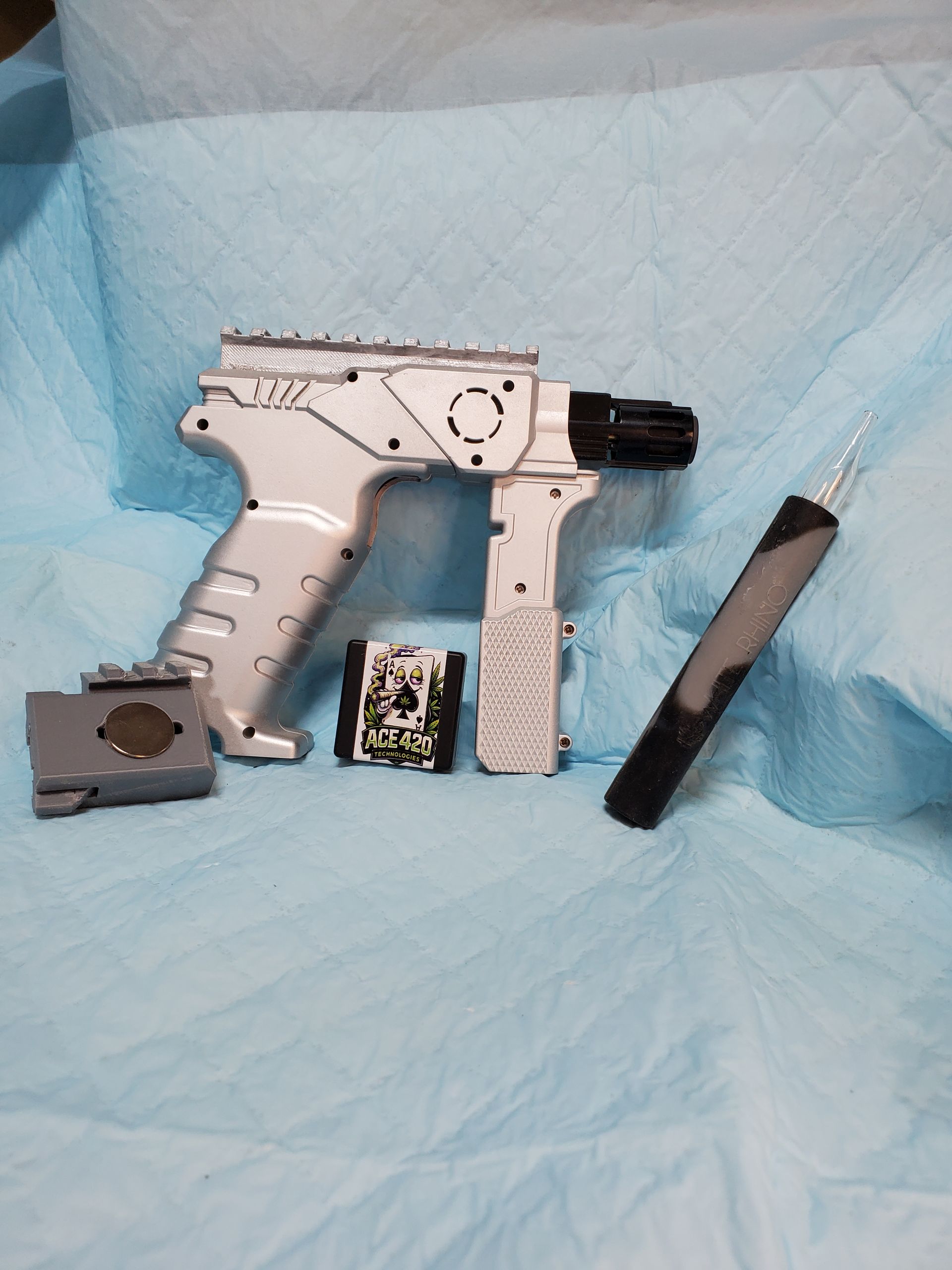 Disassembled silver handgun parts on a blue cloth background.