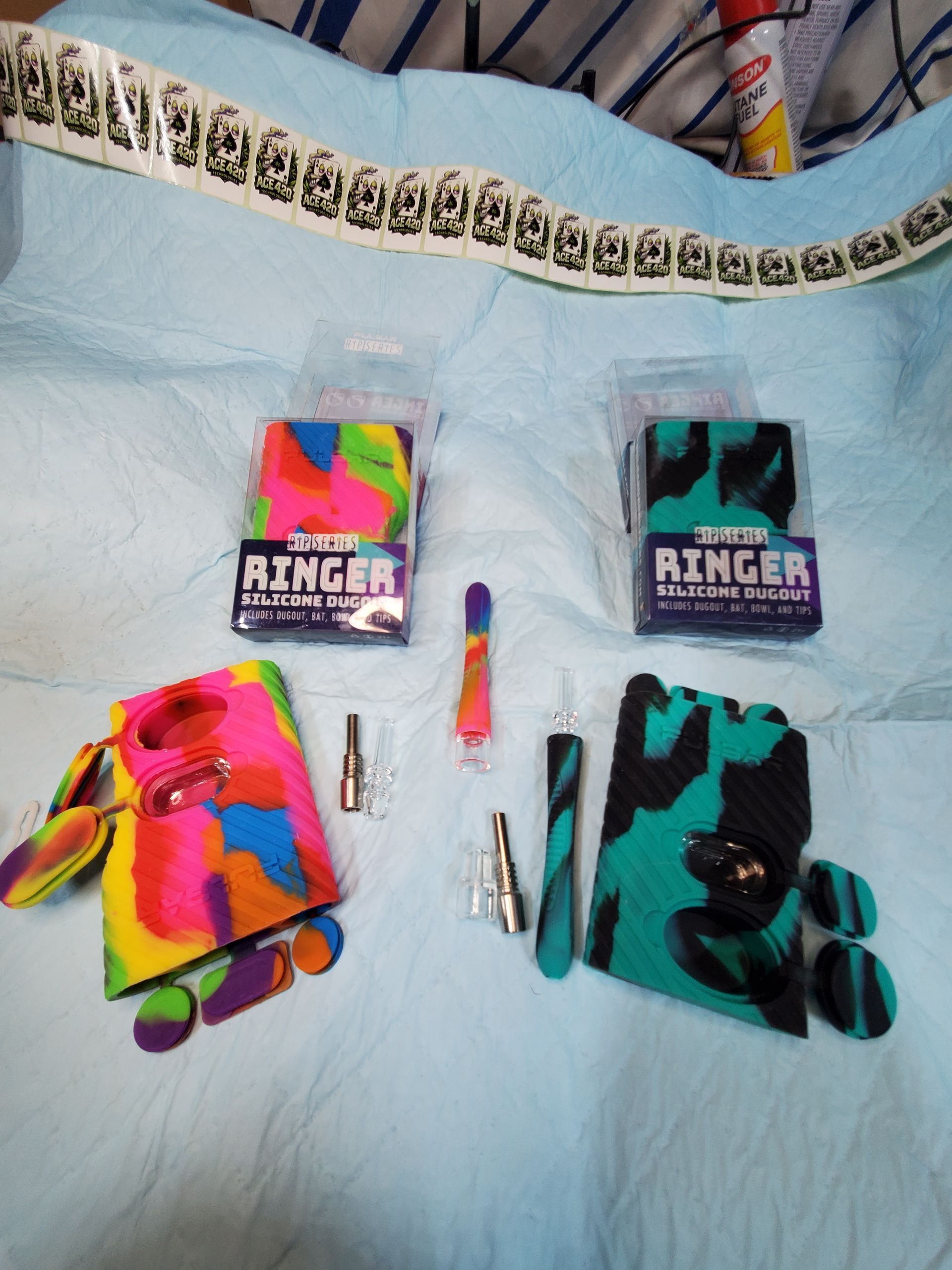 Two colorful toy packages with small accessories and folded fabric items on a light blue blanket