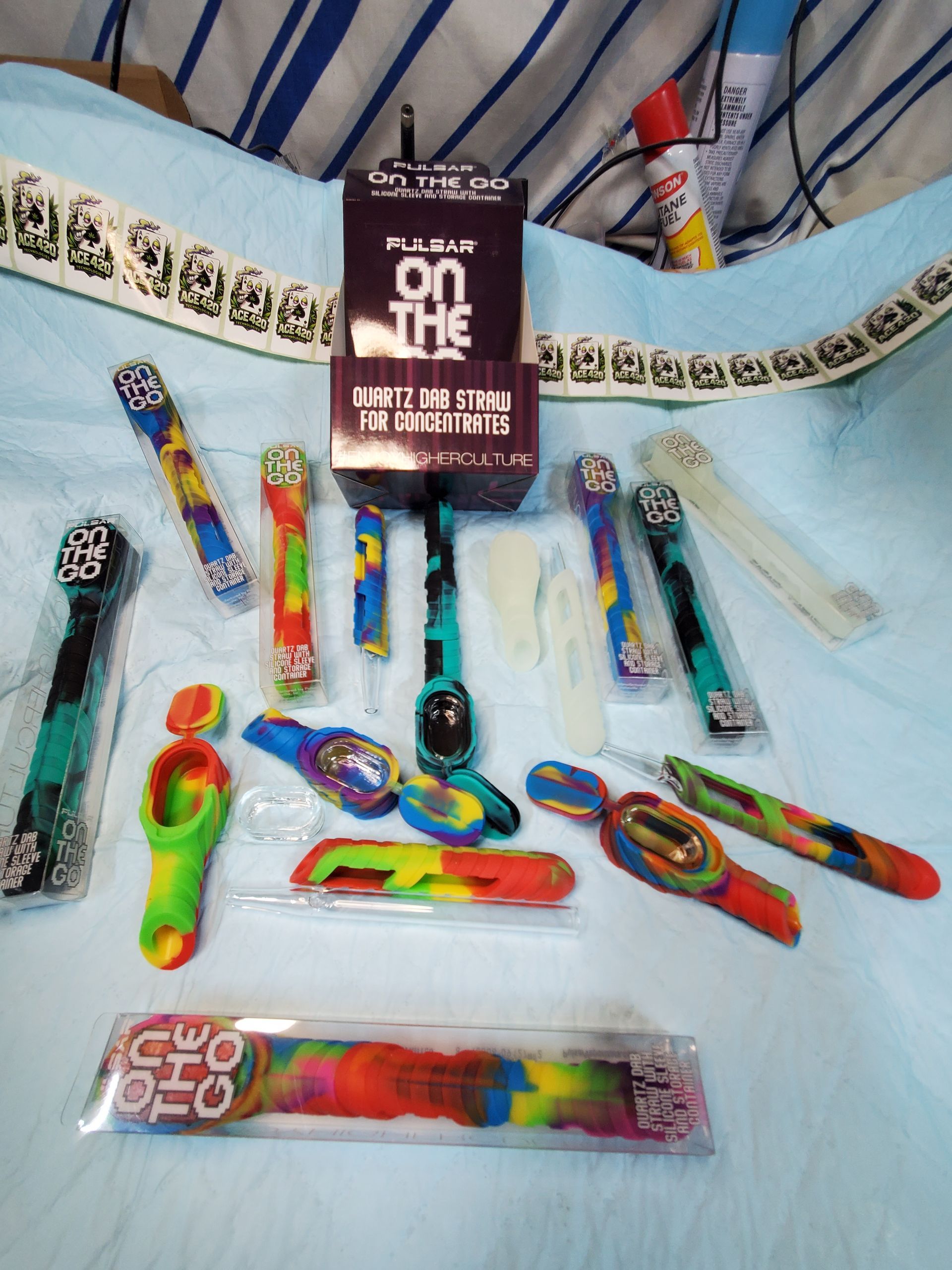Assorted colorful rainbow-themed wands and accessories displayed on a white cloth with a central package.