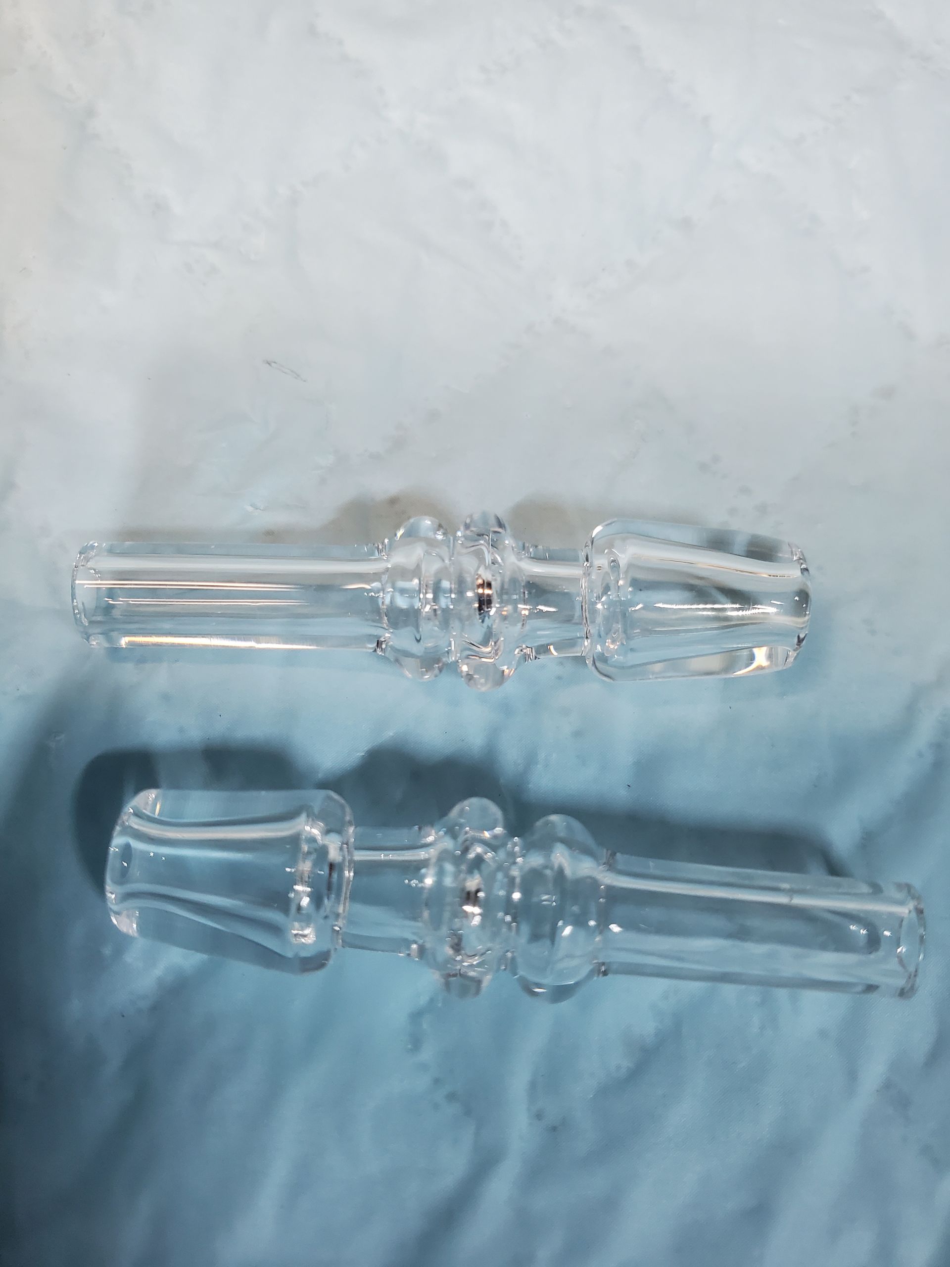 Two clear glass candlesticks on a pale fabric background