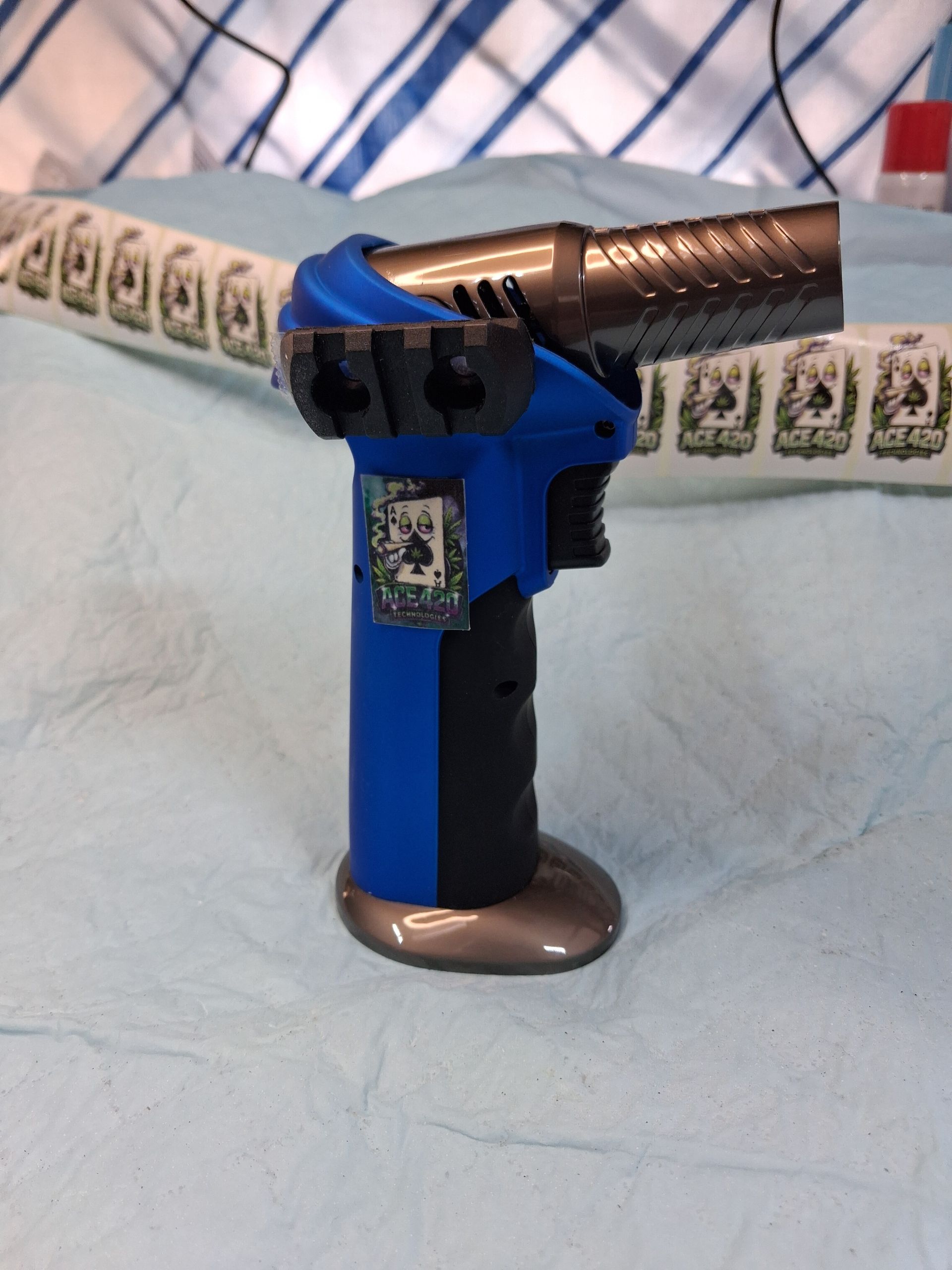 Blue and black electric can opener on a light blue cloth with a patterned towel backdrop