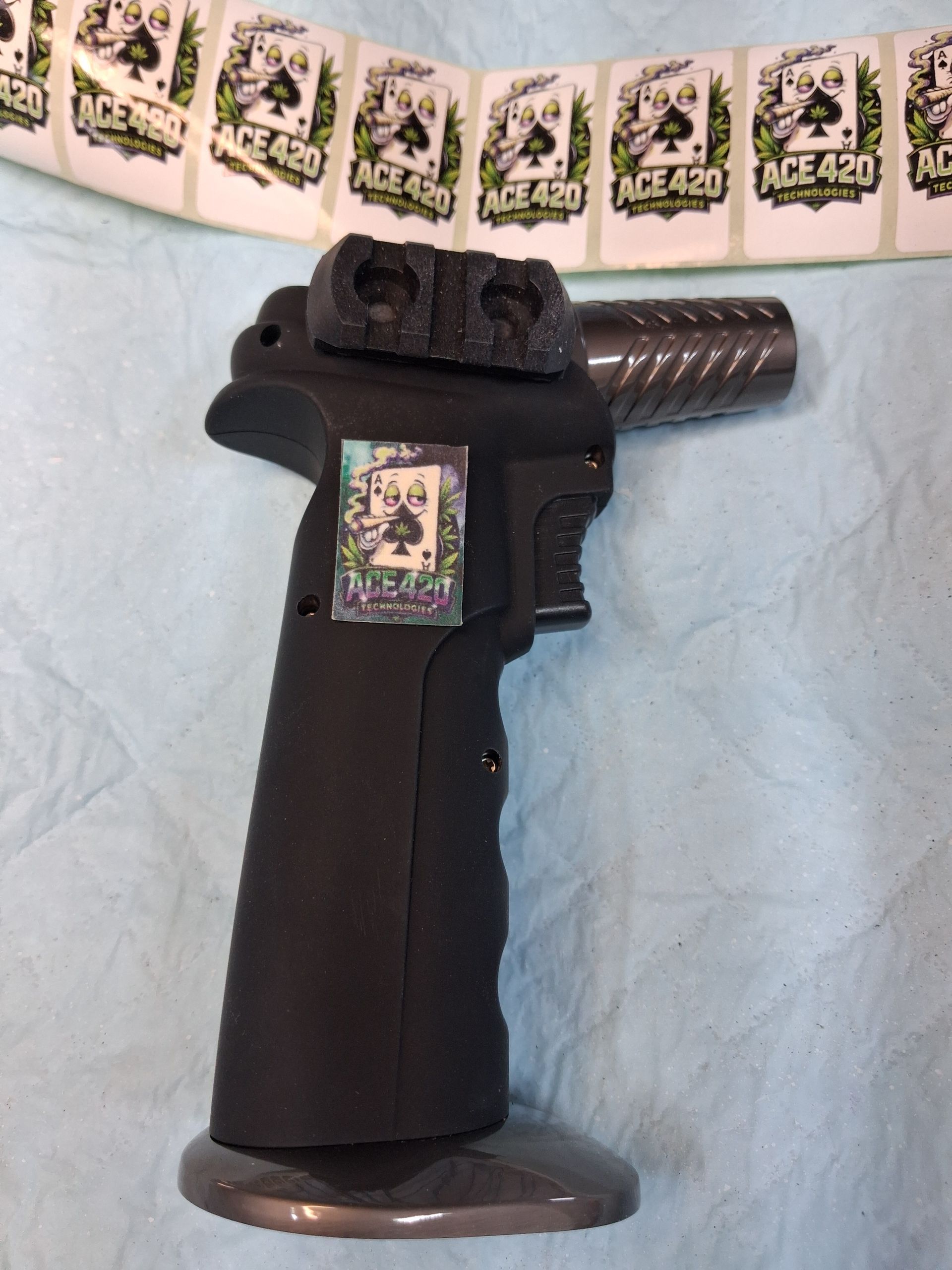 Black handgun-shaped object on a light blue surface, with matching decorative tags hanging above.