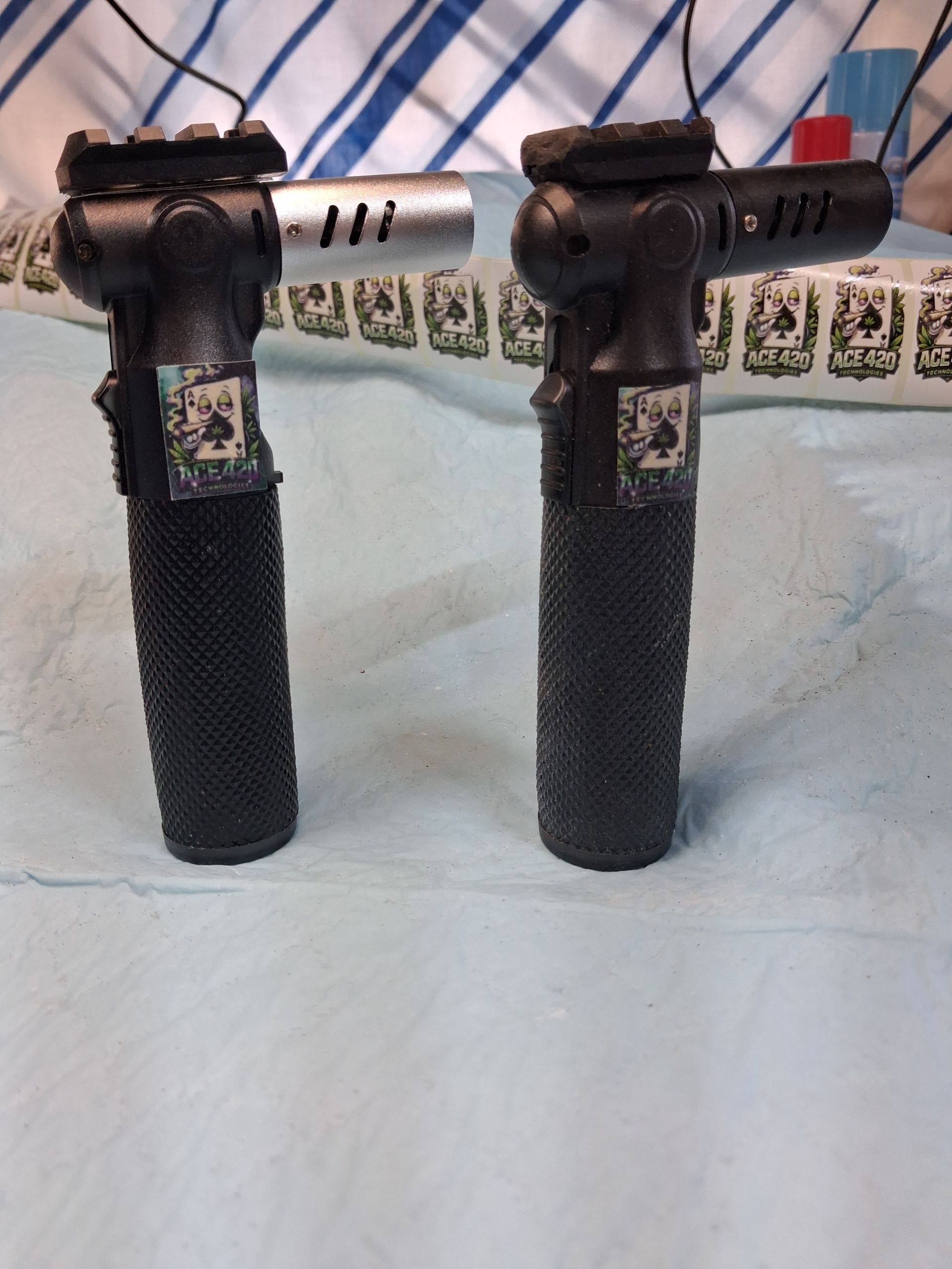 Two black bicycle grips with silver and red handlebar stems, standing upright on a bed.