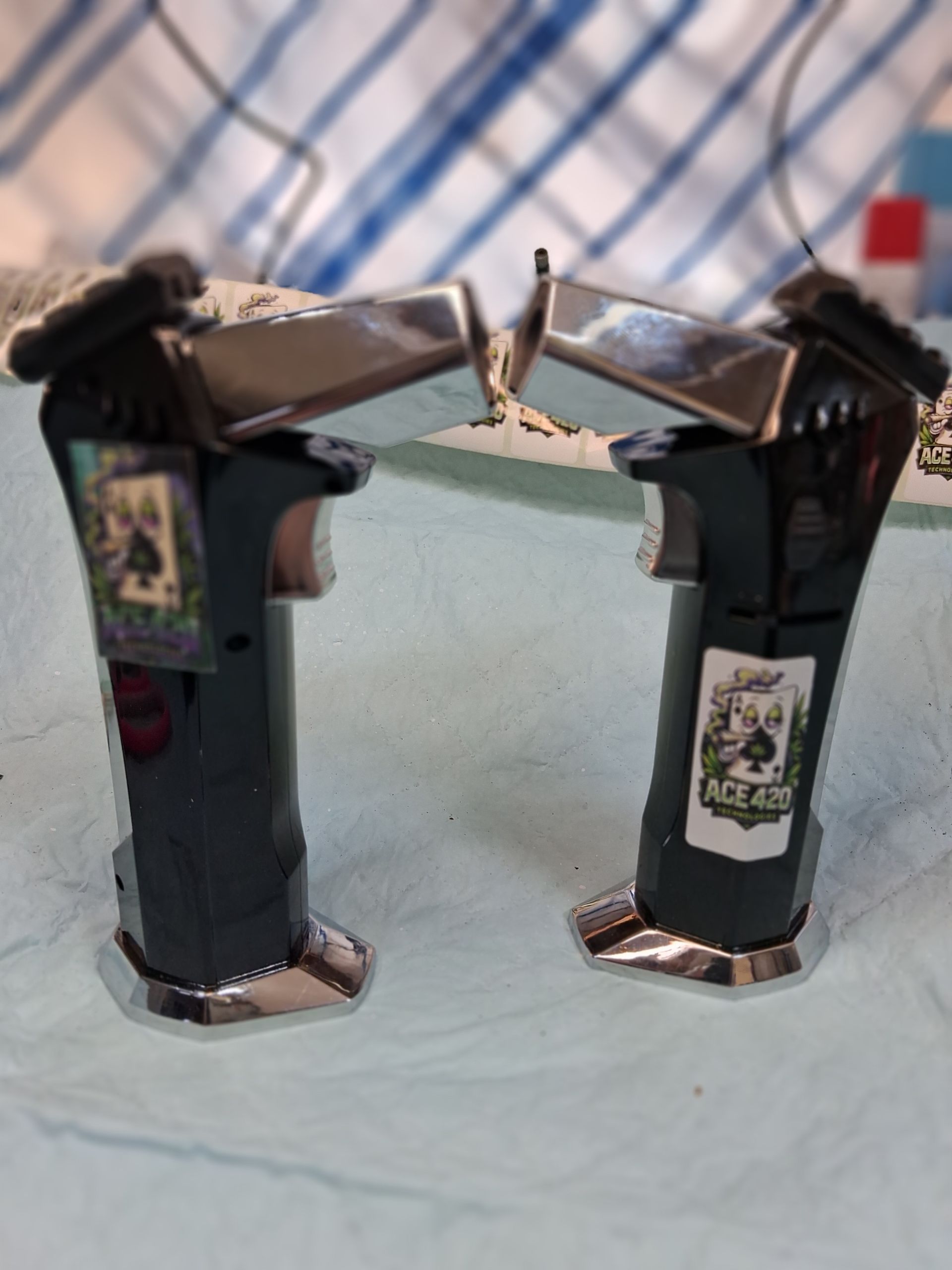 Two black toy guns facing each other on a blue cloth, with silver details and stickers.