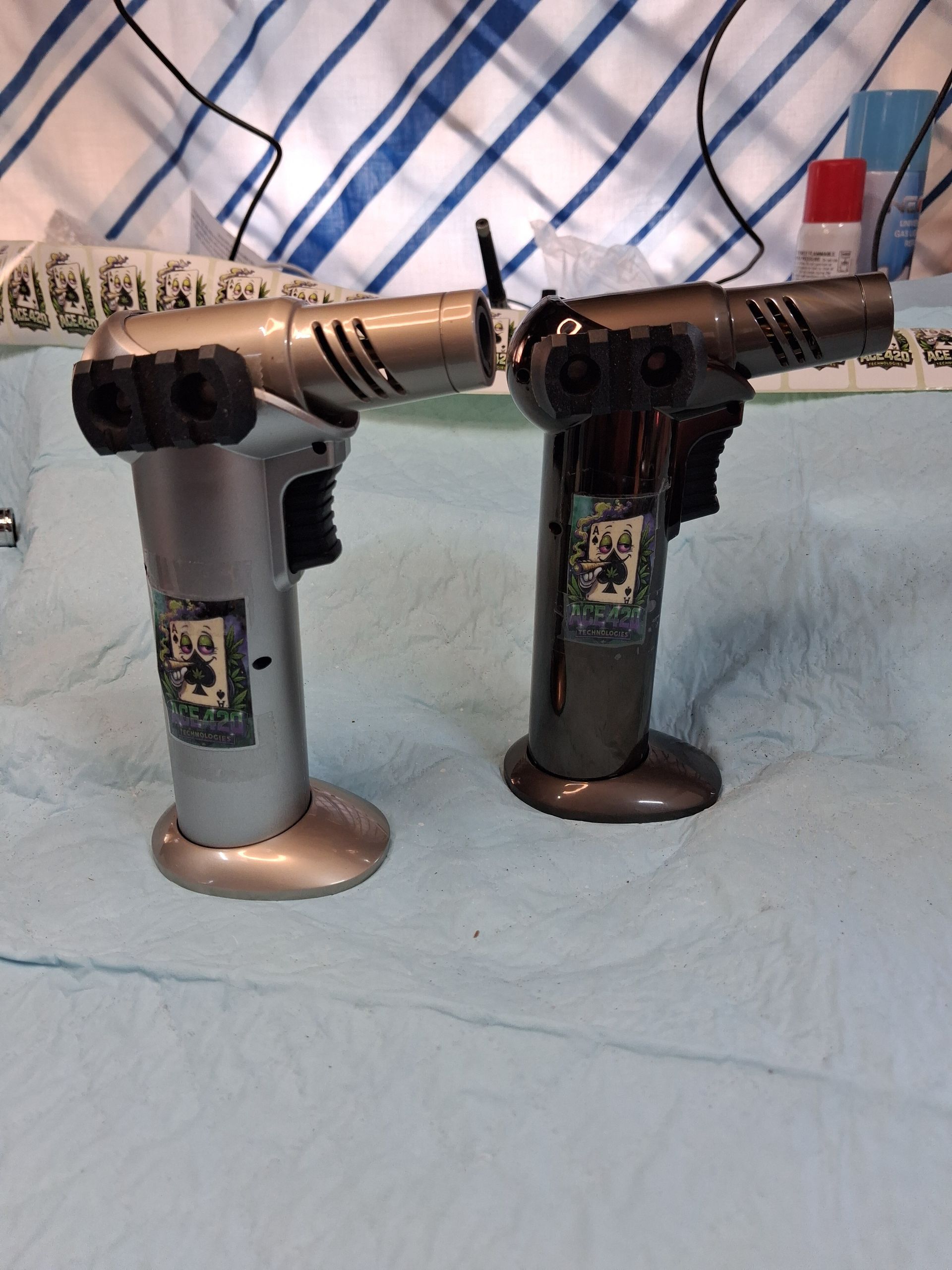 Two toy handguns standing upright on a blue cloth, with a plaid blanket in the background.