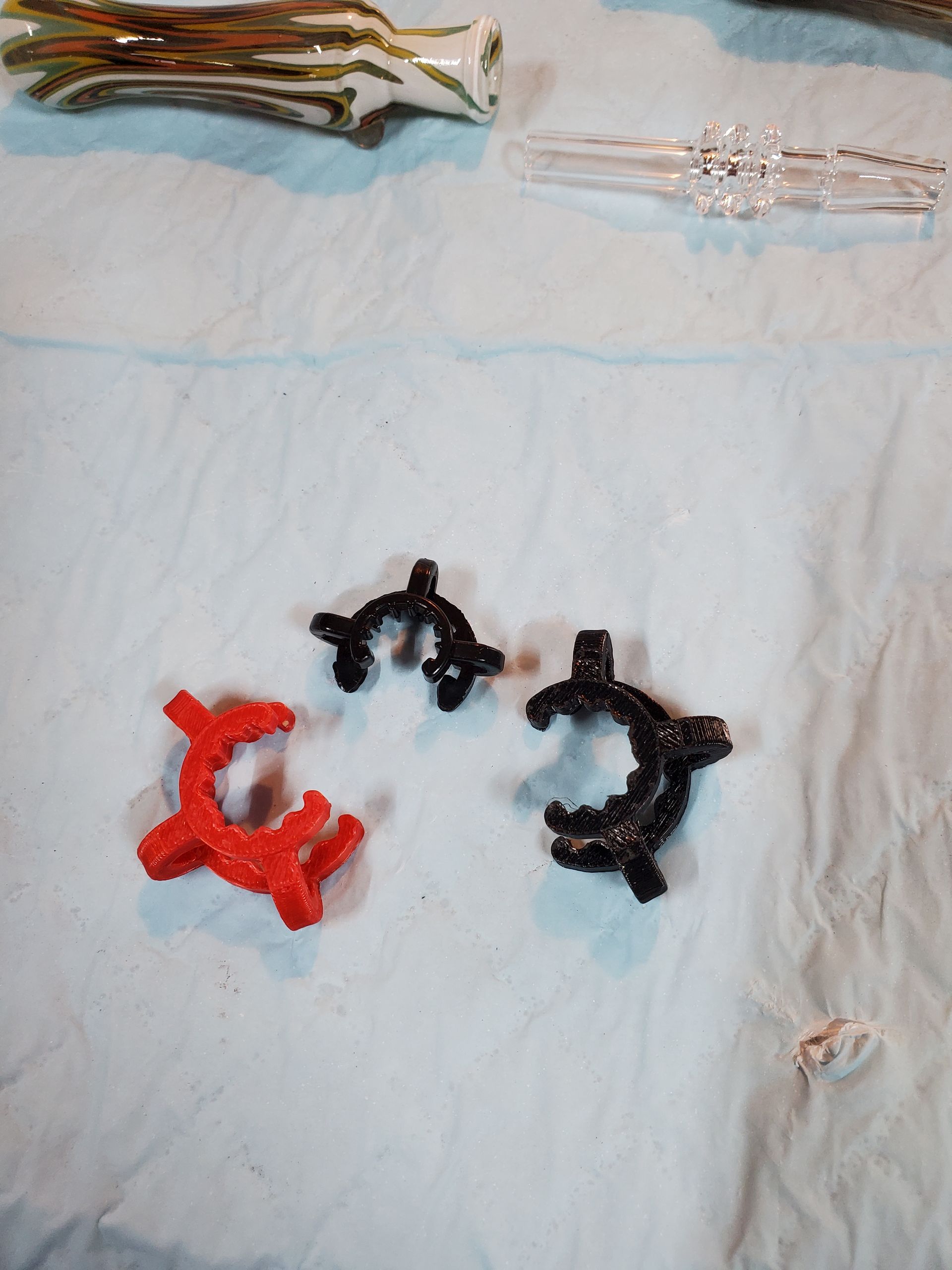 Four small plastic toy clips in red, black, and clear on a light fabric surface