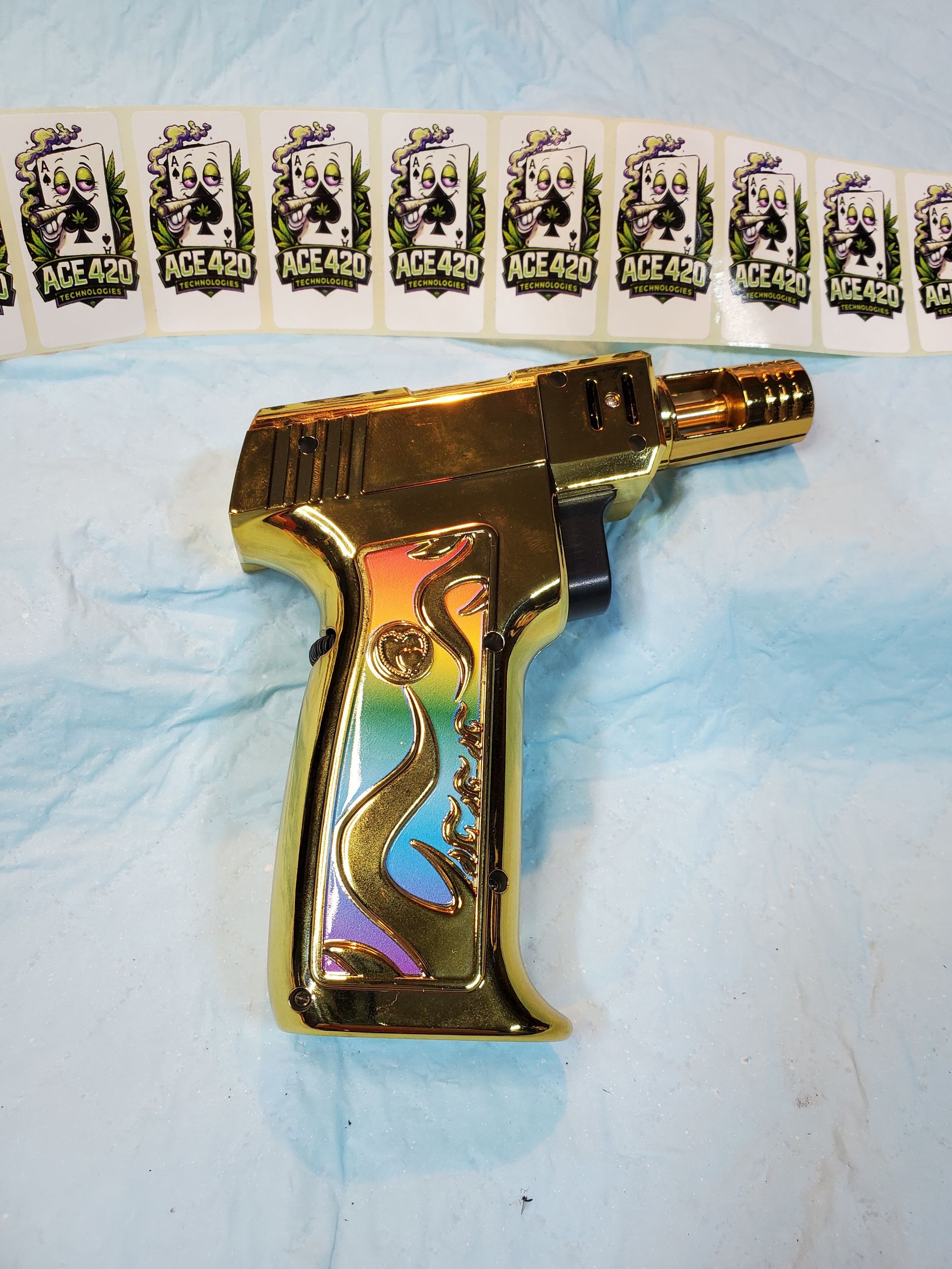 Gold toy pistol with rainbow accents on a blue cloth, with a row of playing cards in the background