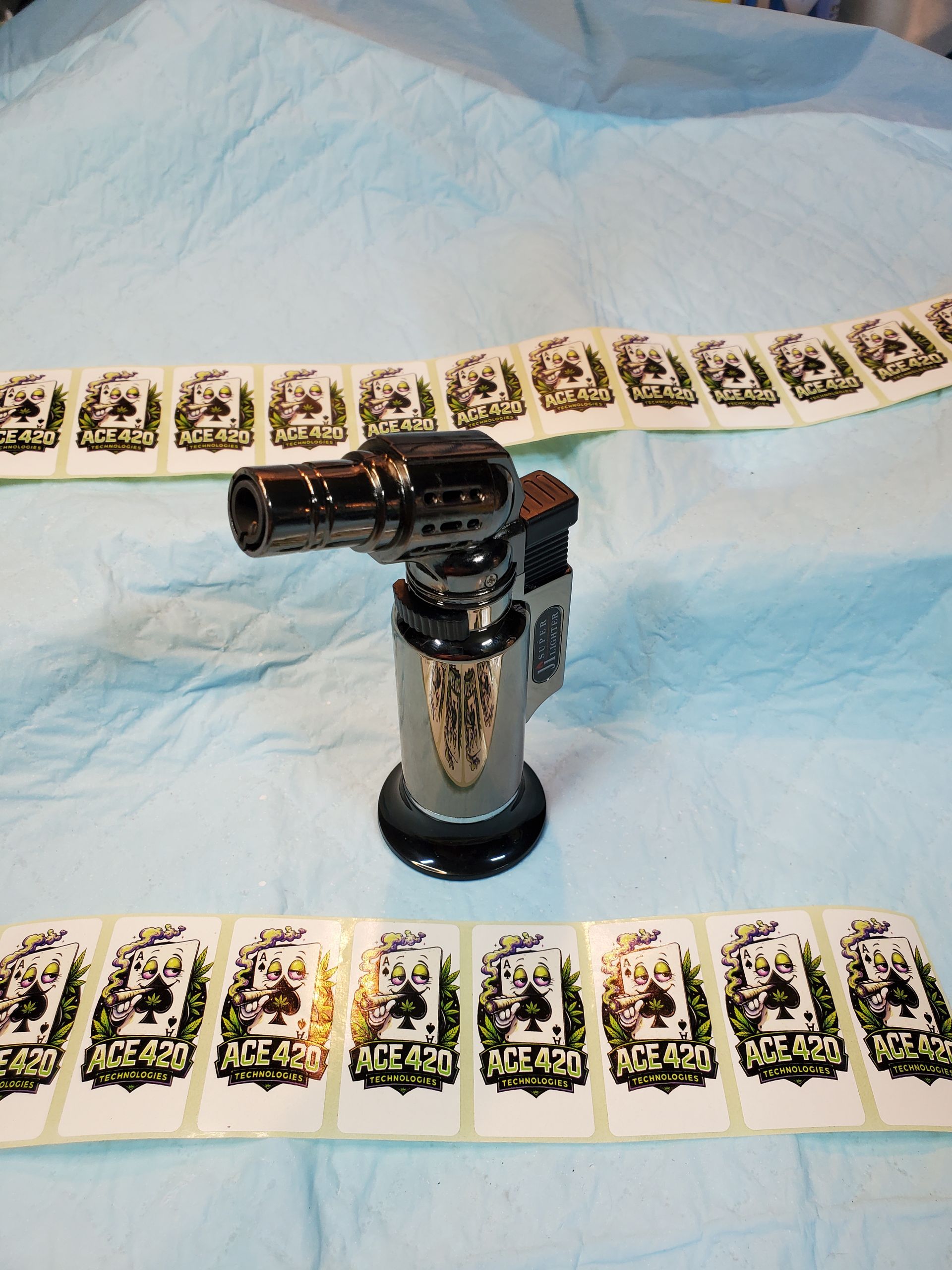 A black lighter stands between two rows of face-up playing cards on a light blue cloth.