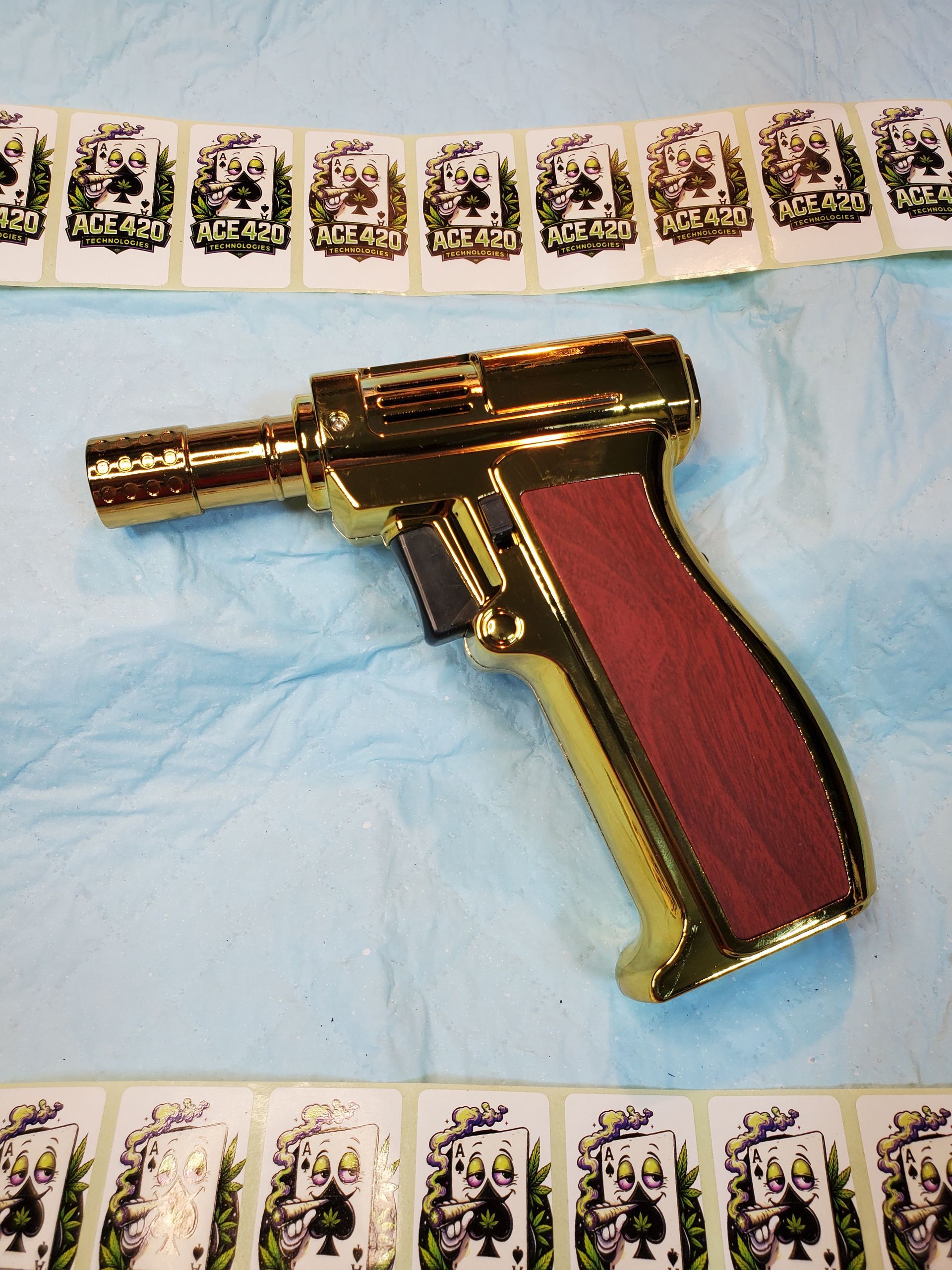 Gold-and-red handheld device lying on blue fabric, bordered by rows of small printed cards.
