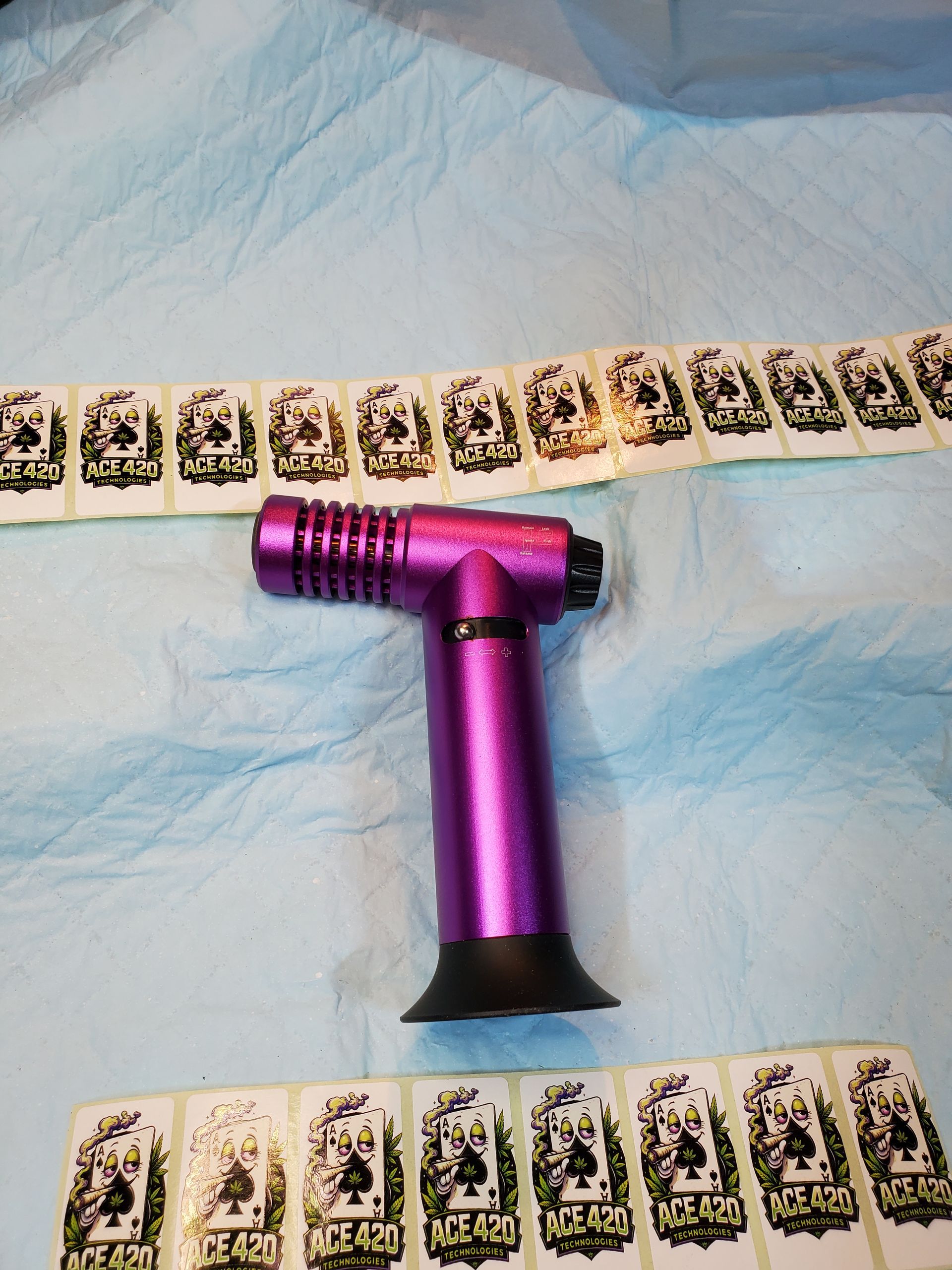 Magenta T-shaped bottle opener on blue cloth, bordered by rows of playing cards above and below