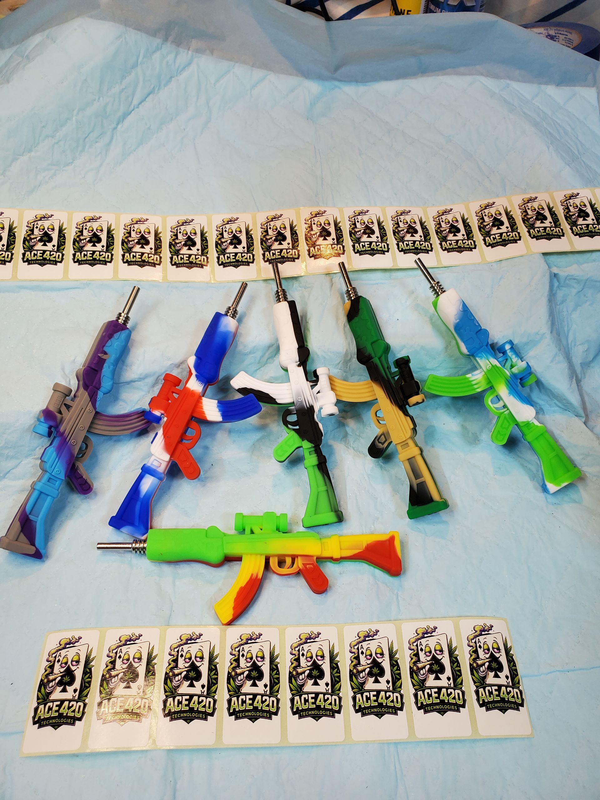 Assorted colorful toy guns arranged on a light blanket with rows of playing cards above and below
