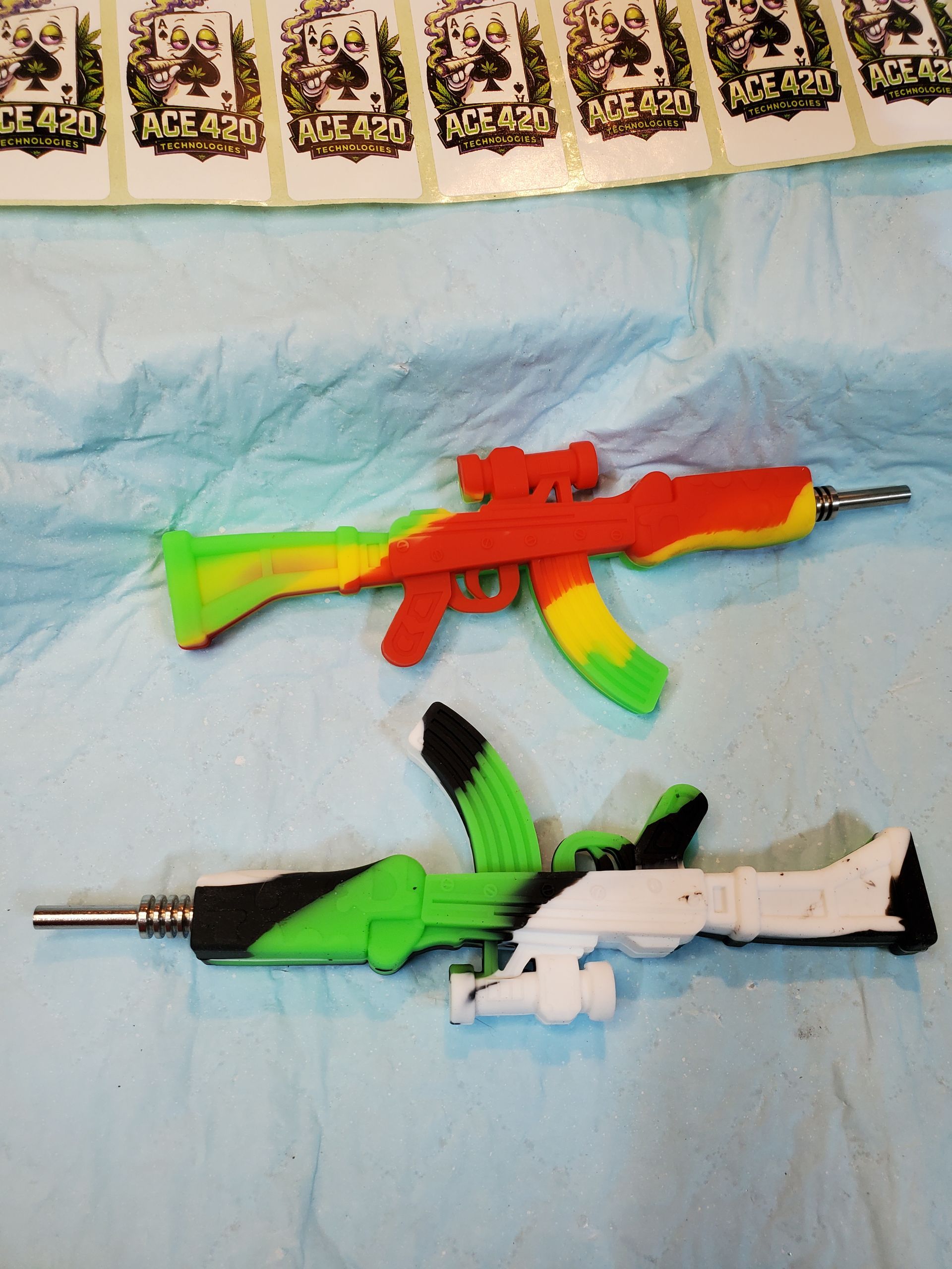 Two colorful toy rifles on a blue cloth, one red and yellow, one black, green, and white.