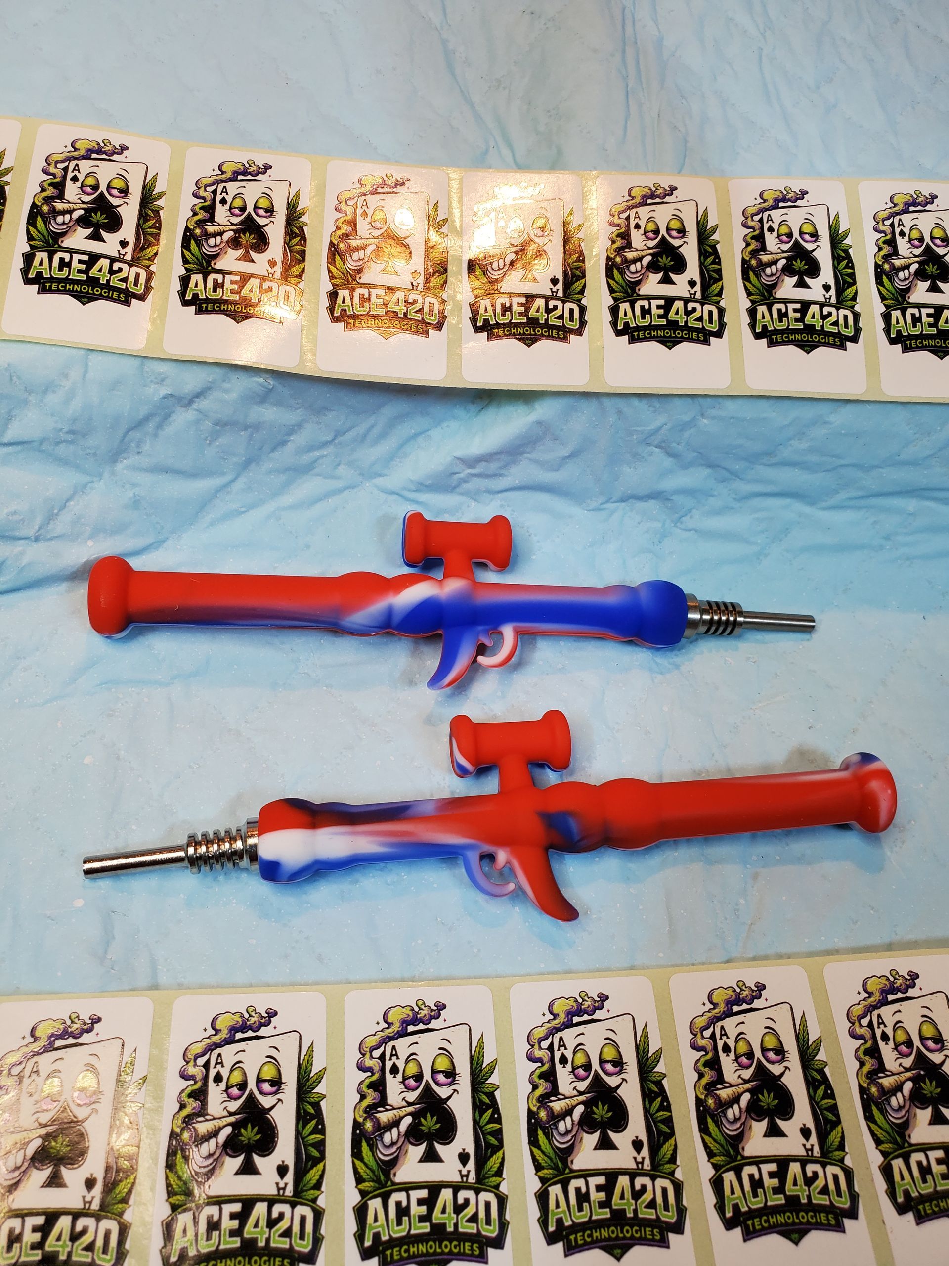 Two toy water guns, red and blue, laid on a blue cloth with ACE 420 cards around them.
