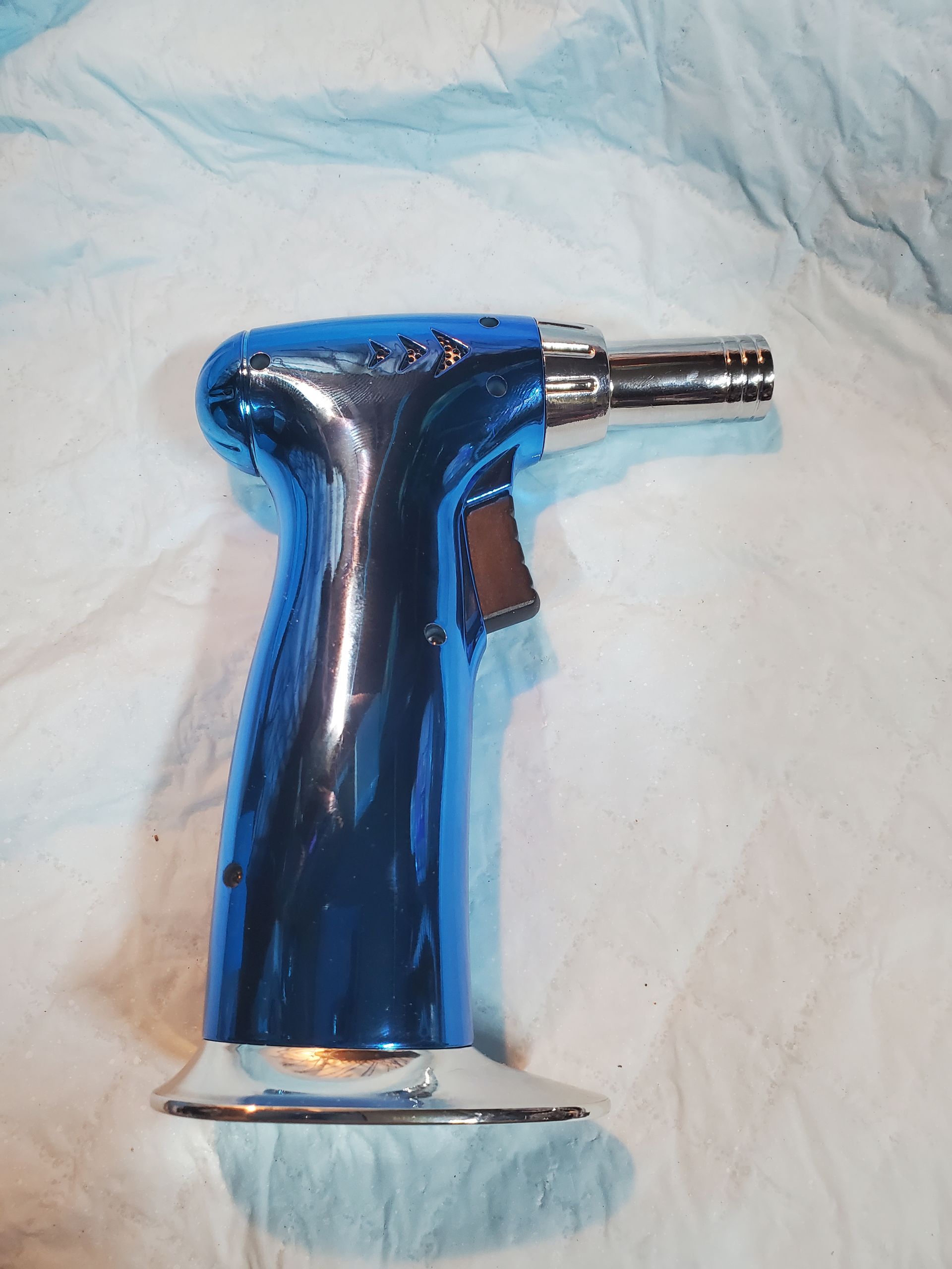 Blue butane torch lighter on a light fabric surface
