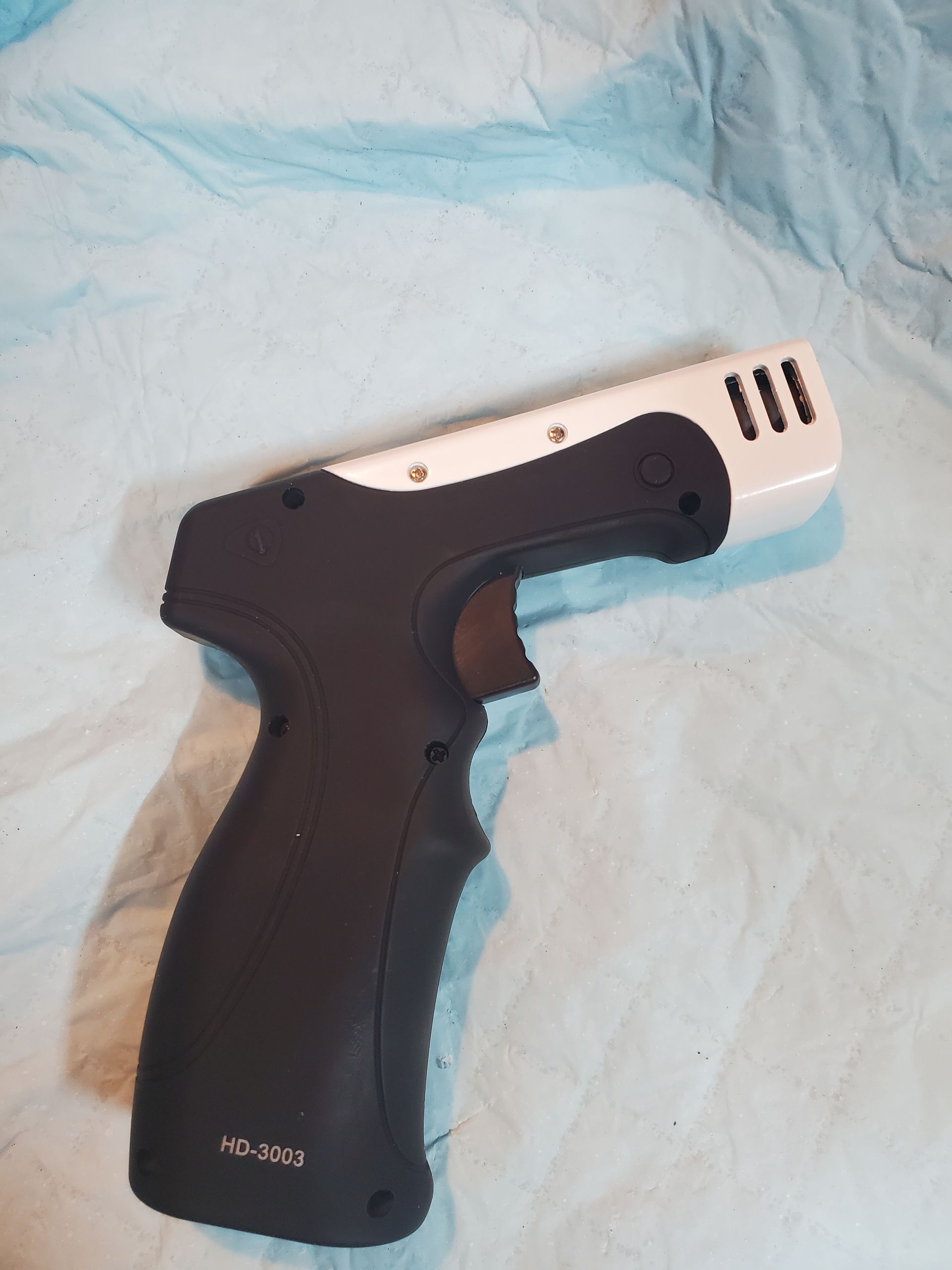 Black-and-silver handheld device on a light blue surface, shown in side view