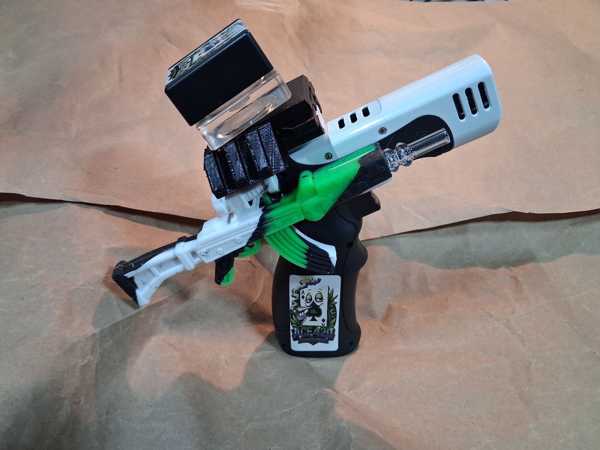 Toy action figure holding a silver and green rifle, wearing a black hat, against a beige background