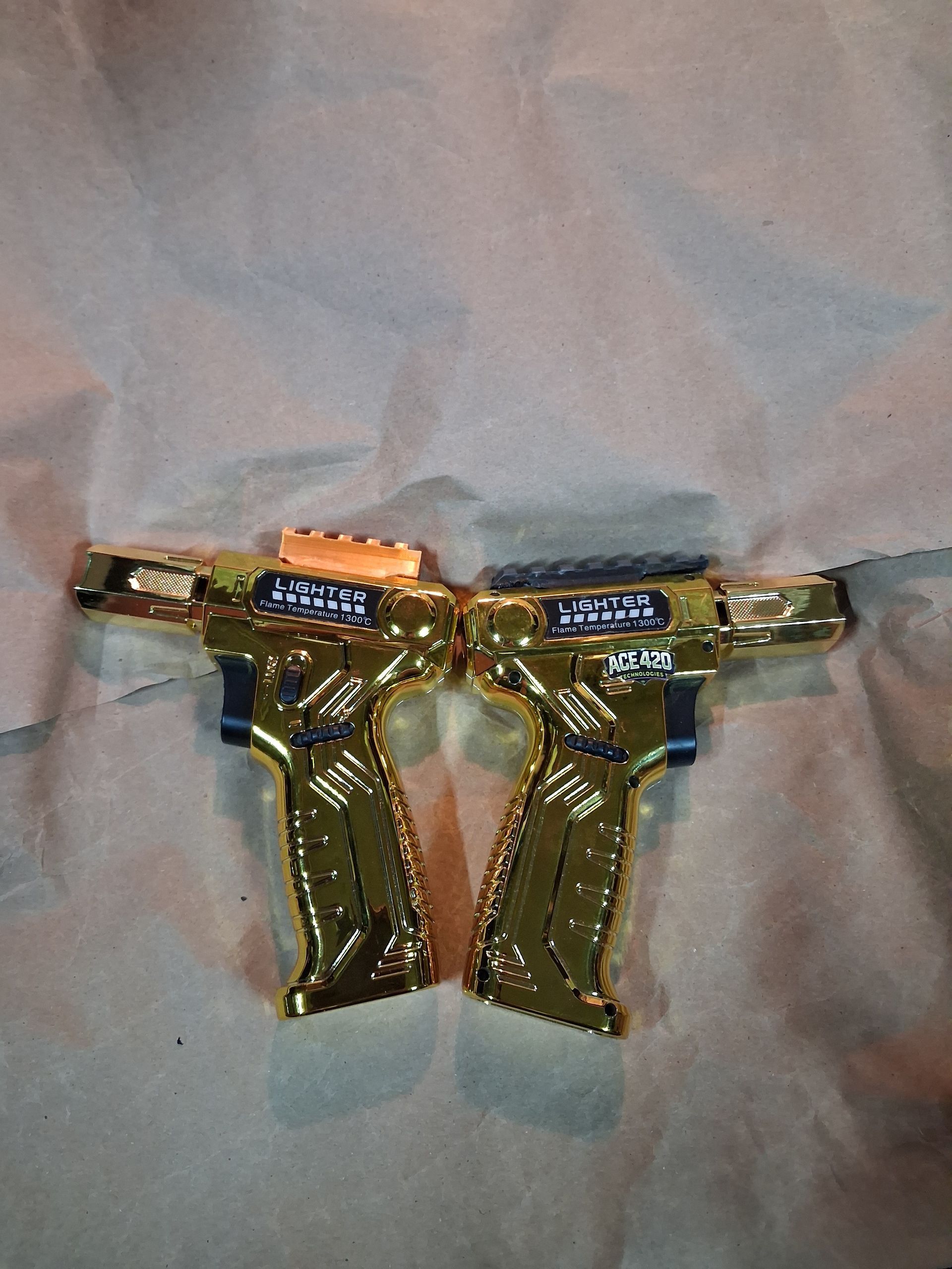 Gold-and-black ornate object with a symmetrical T-shape on a gray fabric background
