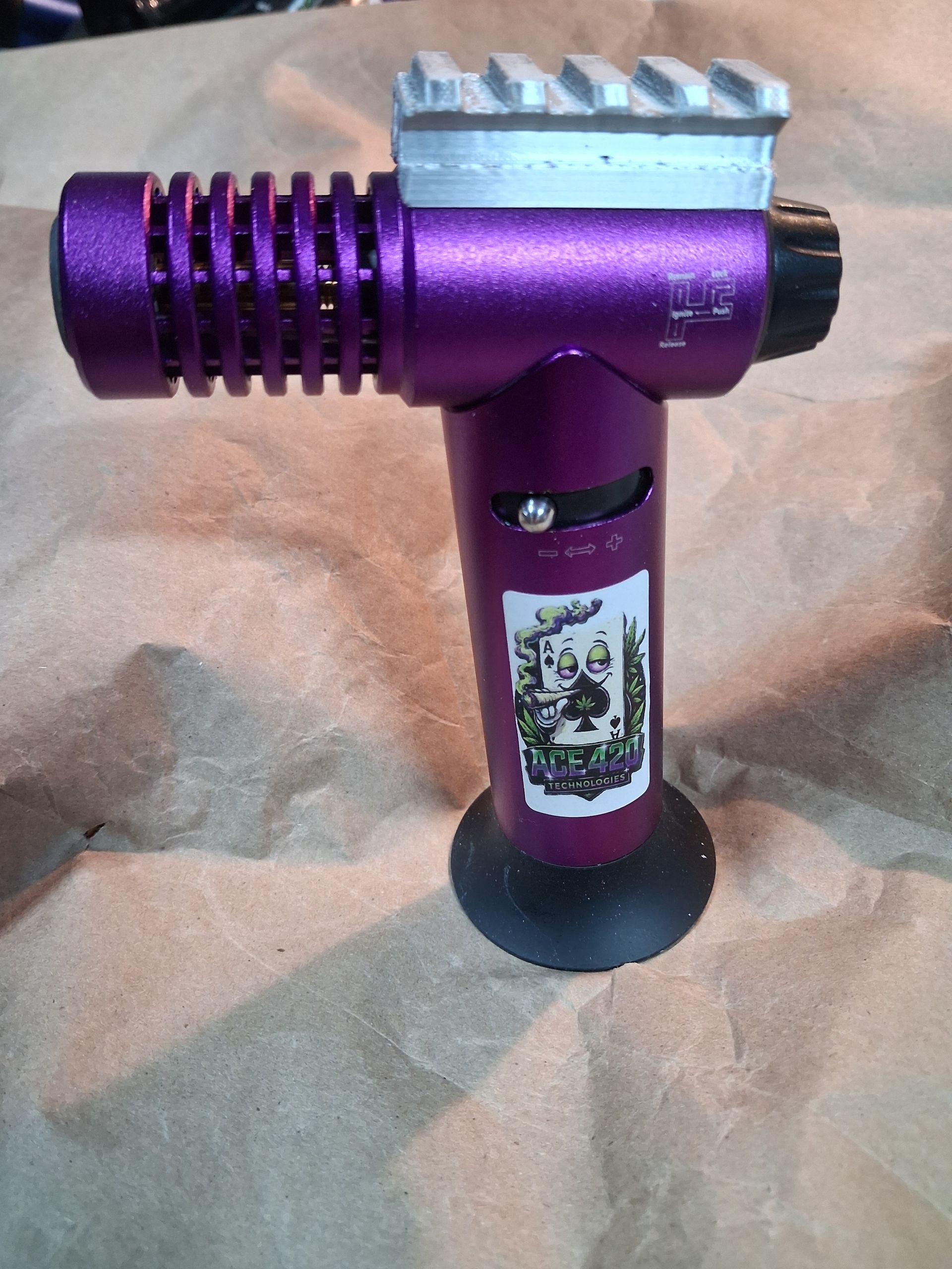 Purple handheld flashlight with a silver top and black base on brown paper.