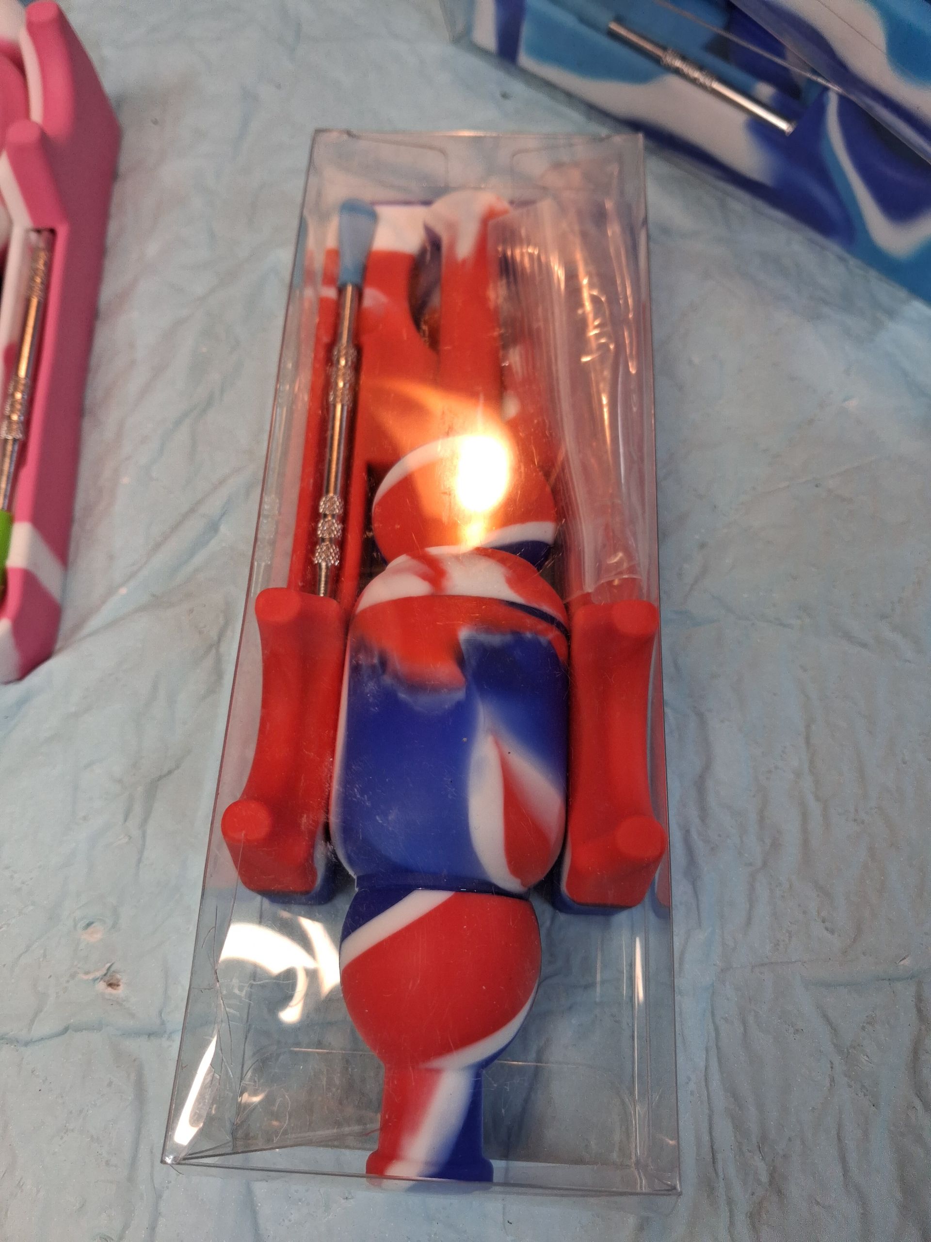Red-and-blue striped action figure in clear plastic packaging on a blue surface.