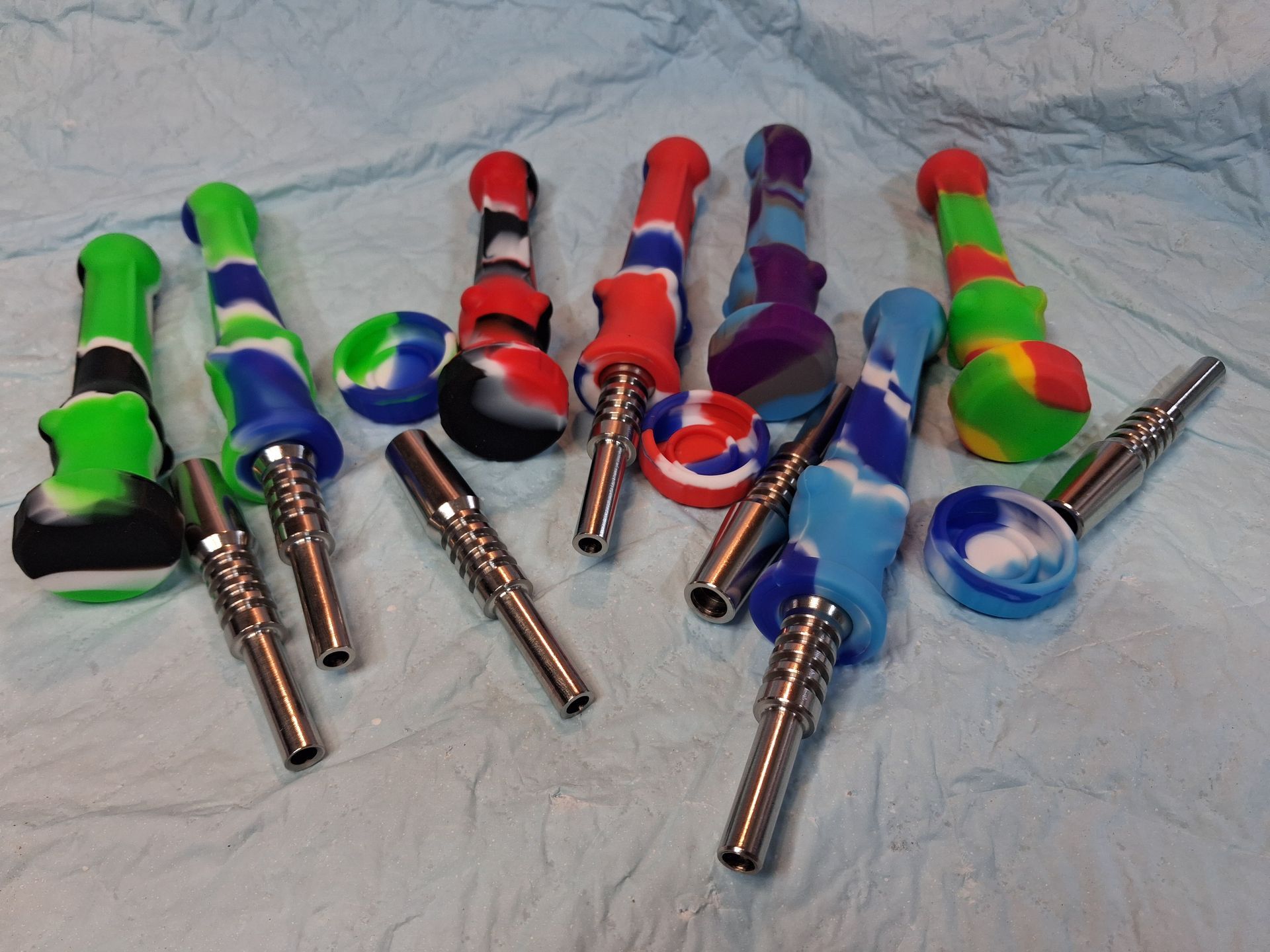 Colorful dab tools and metal tips arranged on a wrinkled white cloth.