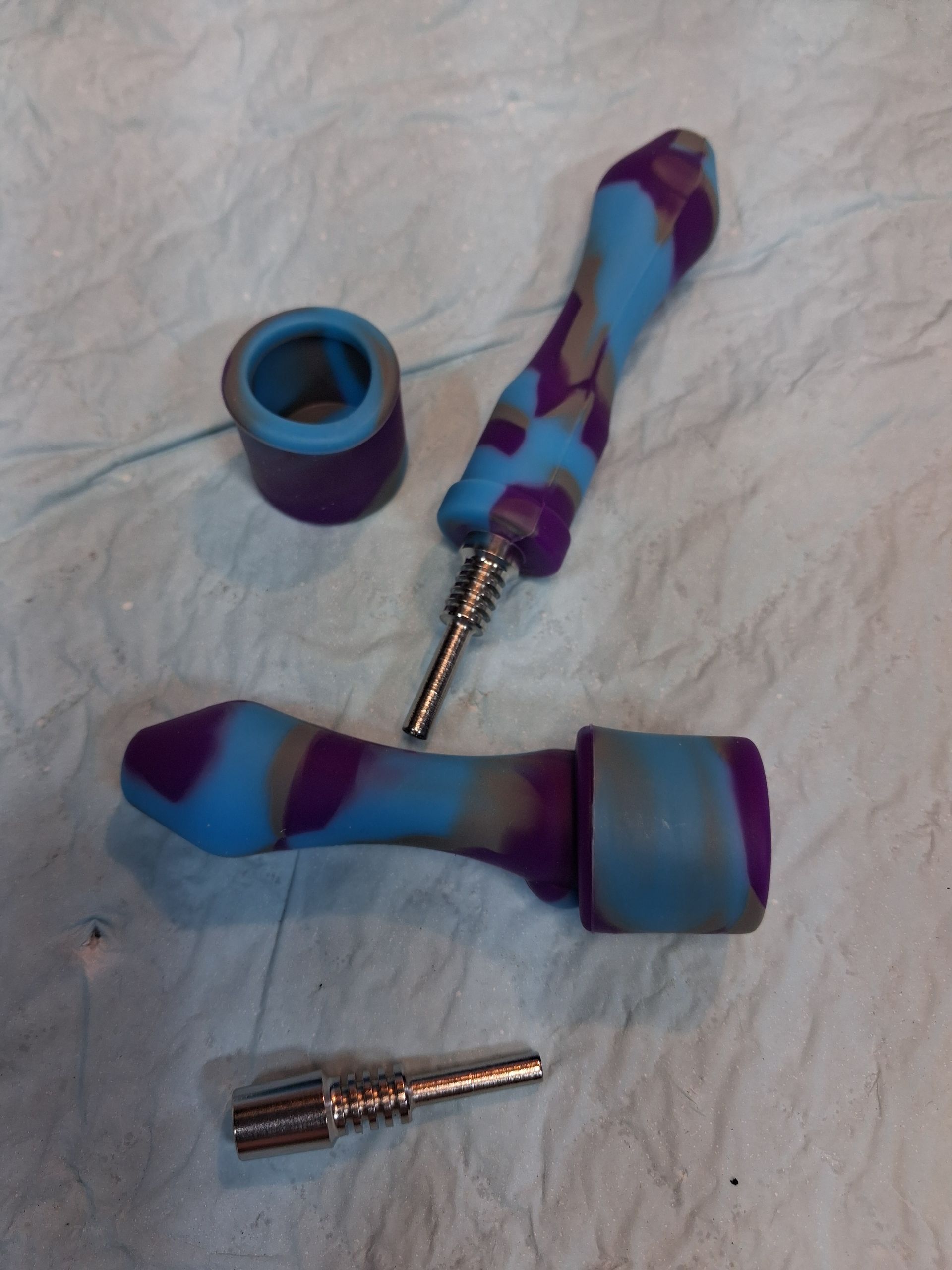 Blue-purple patterned silicone dab tools and a metal connector on a light fabric surface