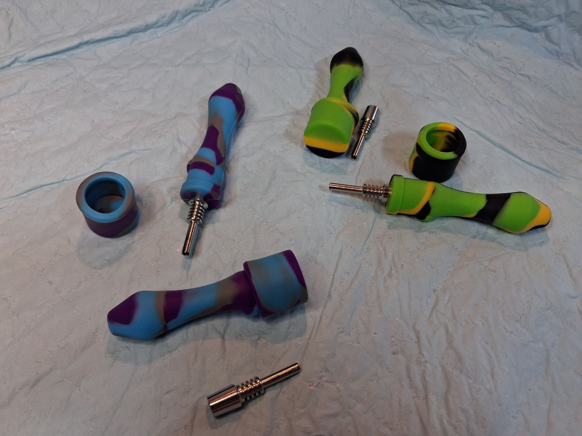 Colorful sock-covered objects and metal plugs scattered on a white cloth surface