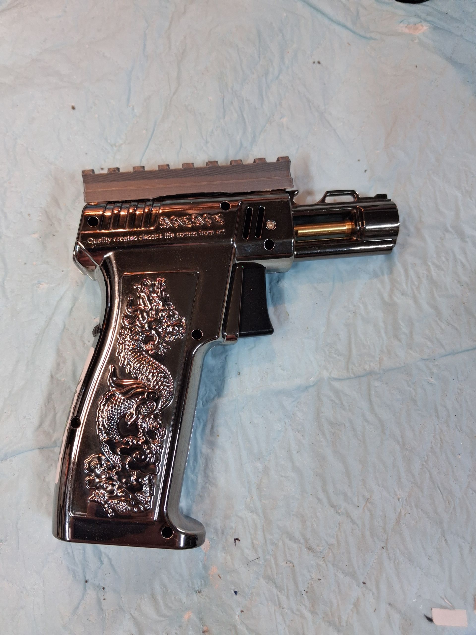 Black handgun on a light blue cloth surface, shown from the side.