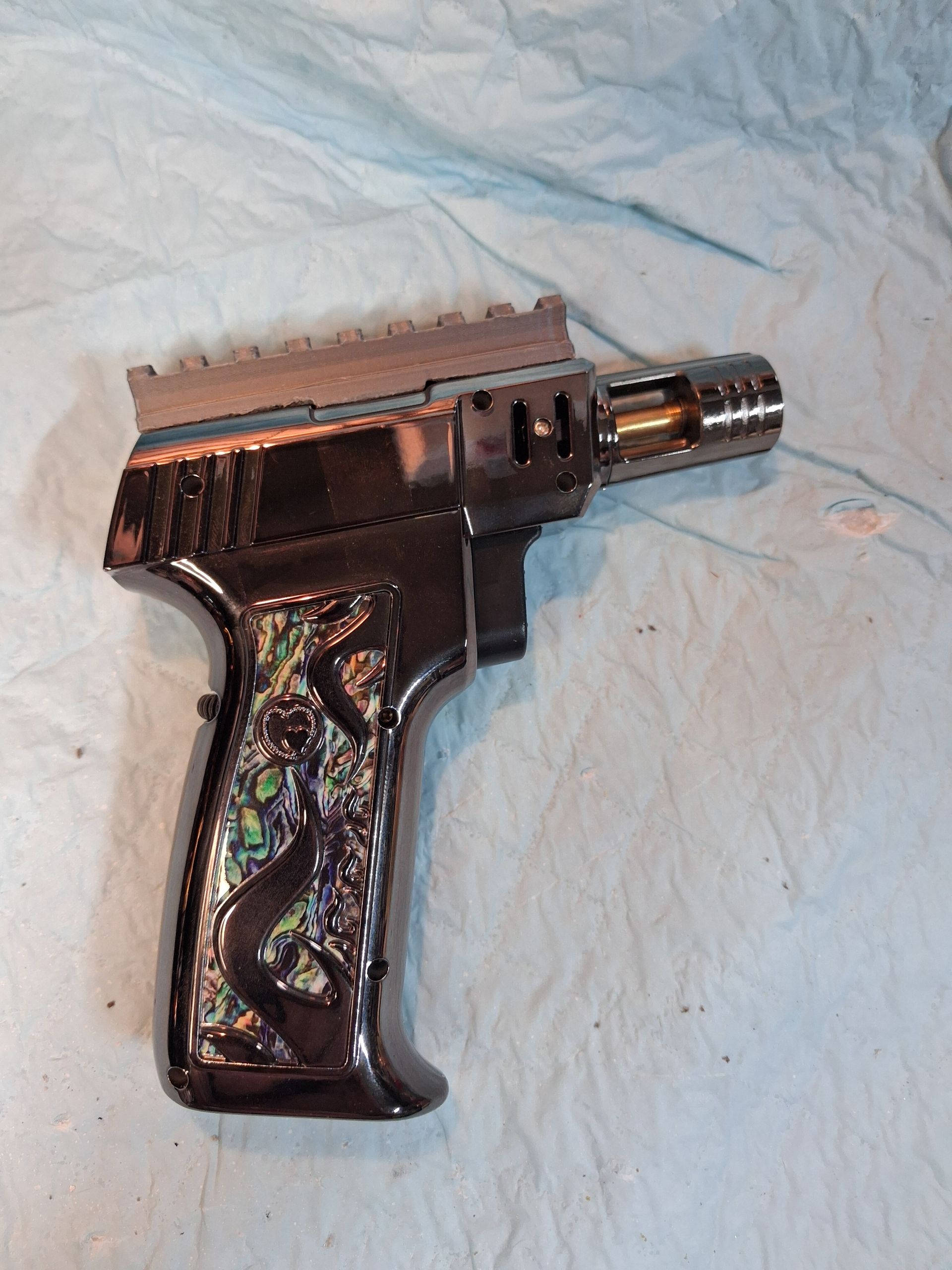 Black handgun with silver barrel on a light blue cloth background