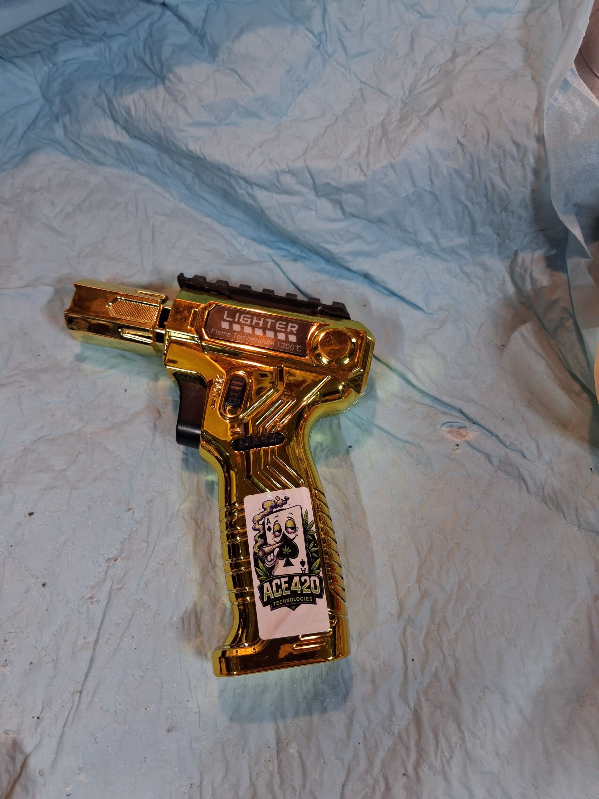 Gold-colored toy gun wrapped in plastic on a crumpled white tissue.