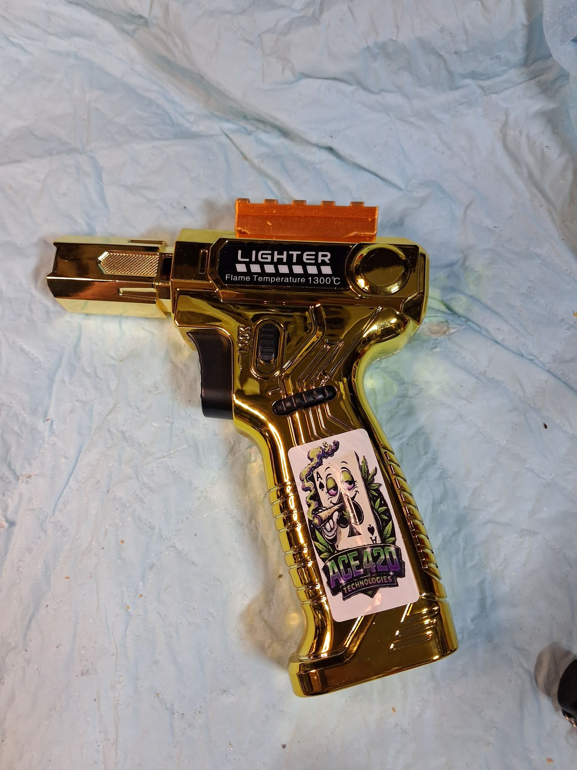 Gold toy gun-shaped lighter on white fabric background