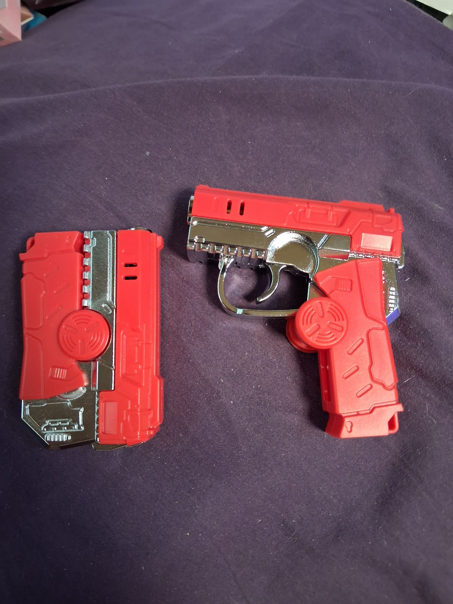 Two small red toy guns on a dark fabric background