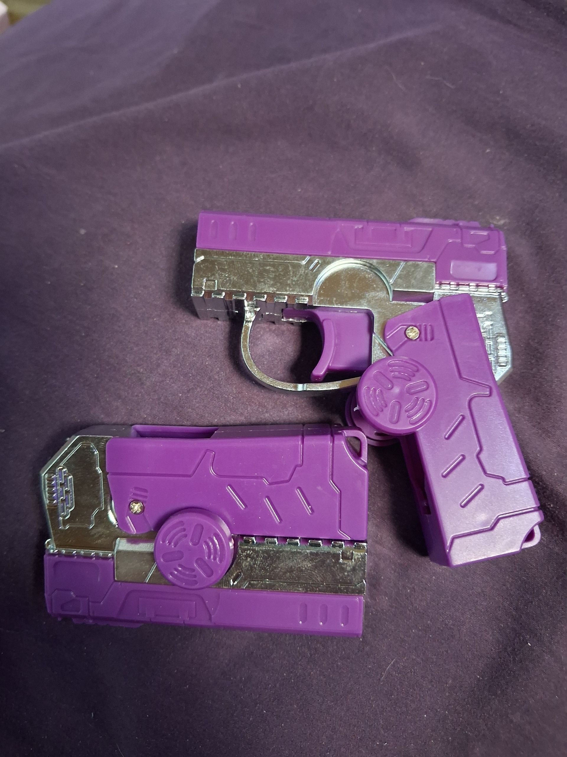 Two purple toy gun models on a dark fabric background