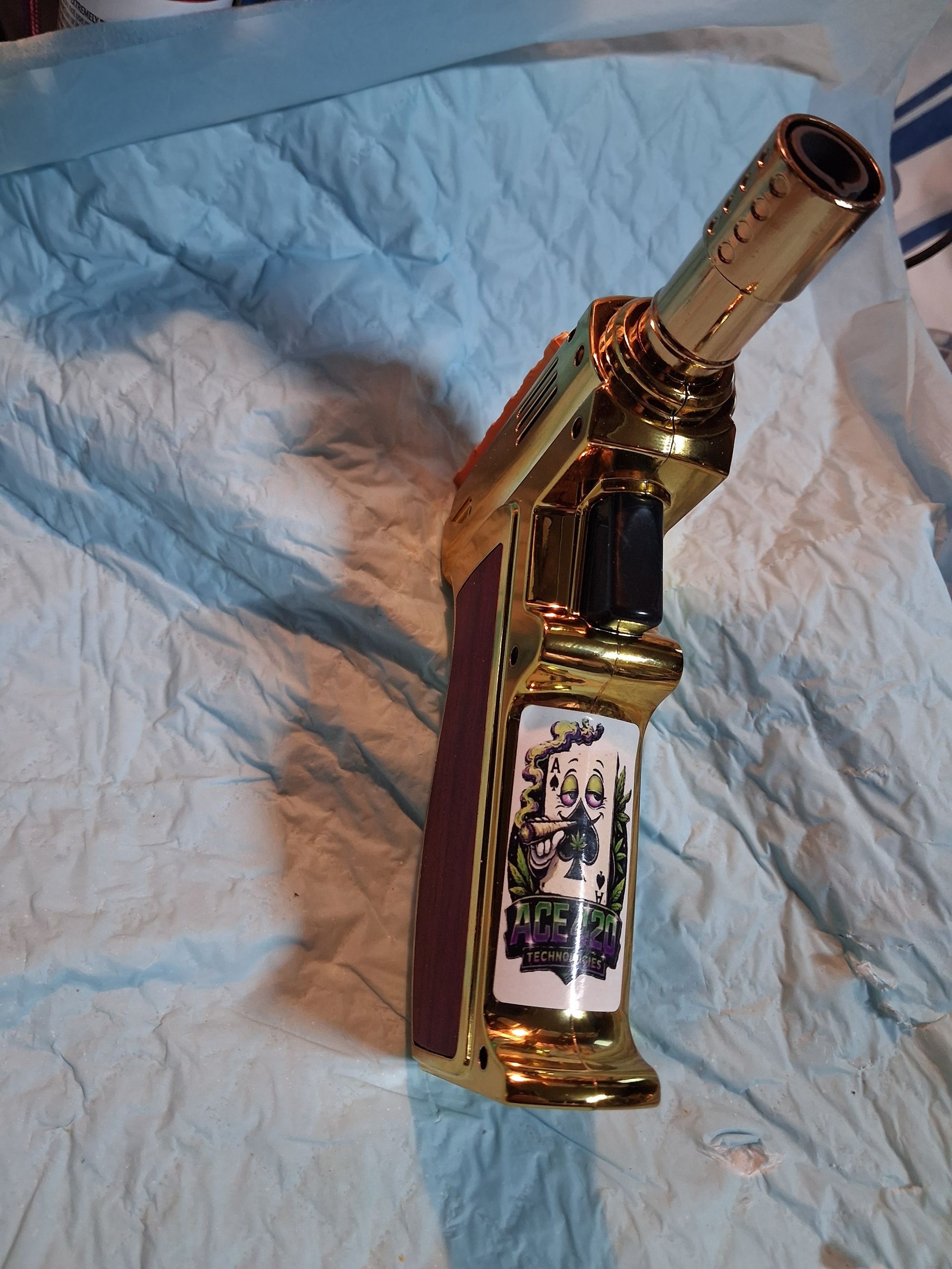 Gold ornate lighter standing on a white quilted blanket.