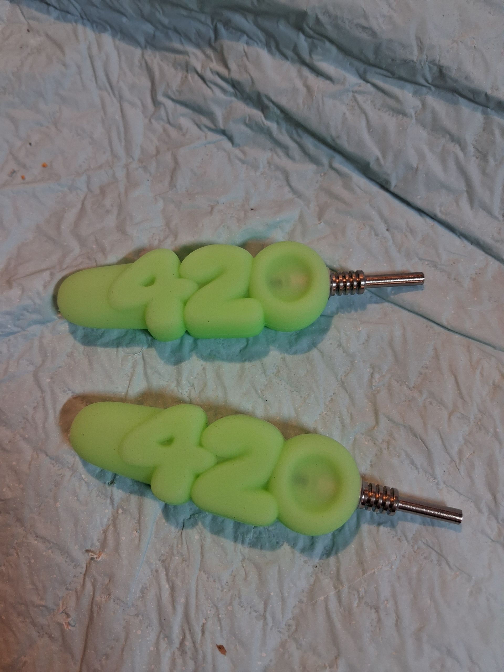 Two neon green handmade keychains with the number 420 on a light fabric background.