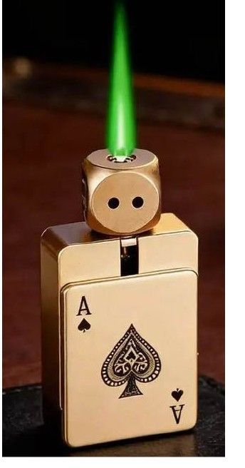 Silver lighter with an Ace of Spades design, emitting a green flame on a dark background