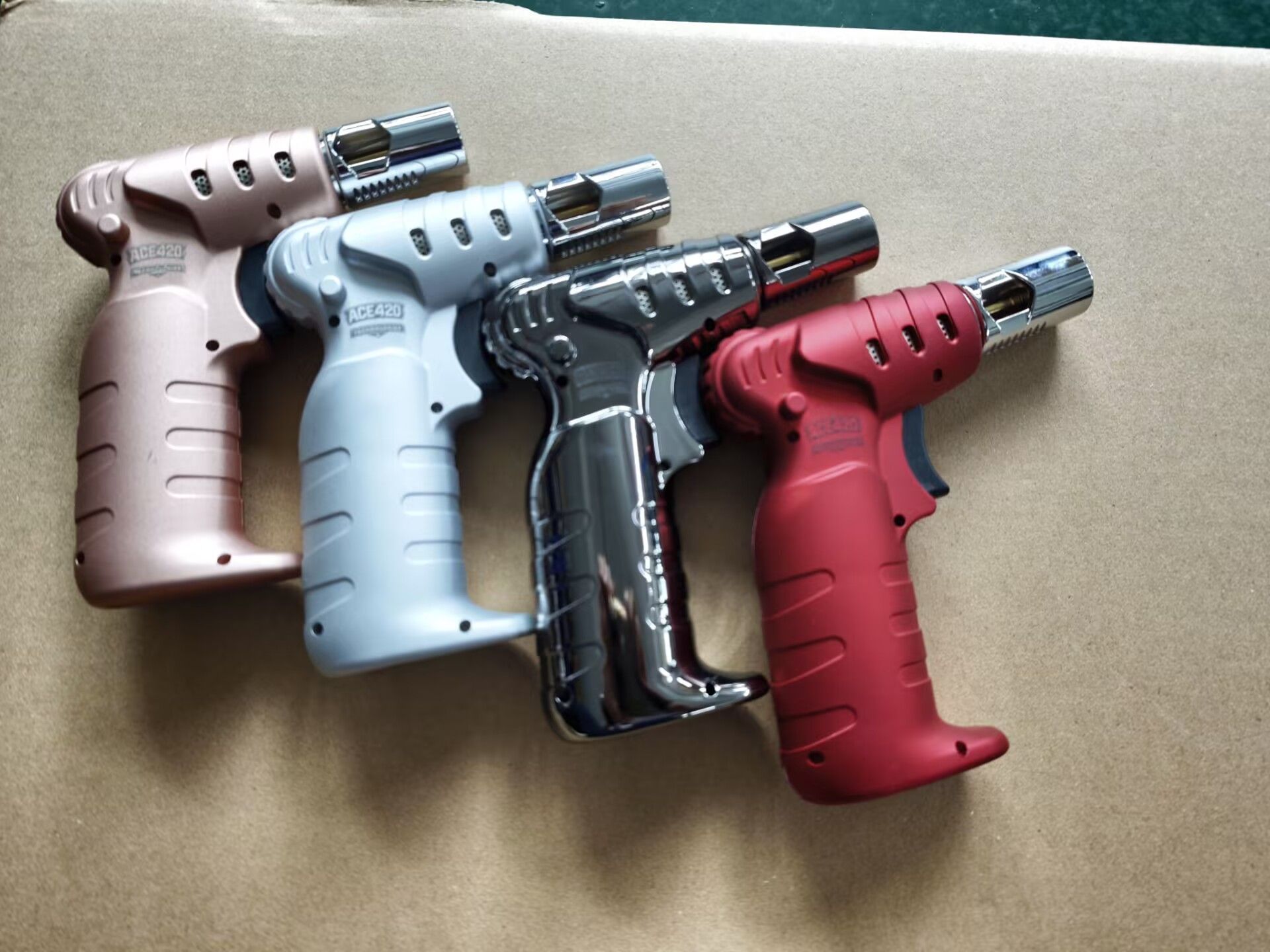 Four colorful handheld lighters arranged side by side on a light surface