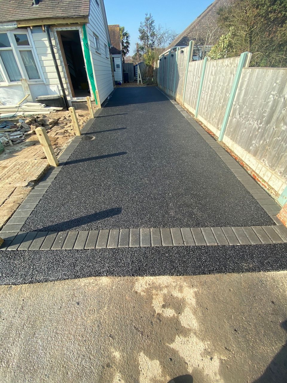 A driveway with a brick border is being built in front of a house.