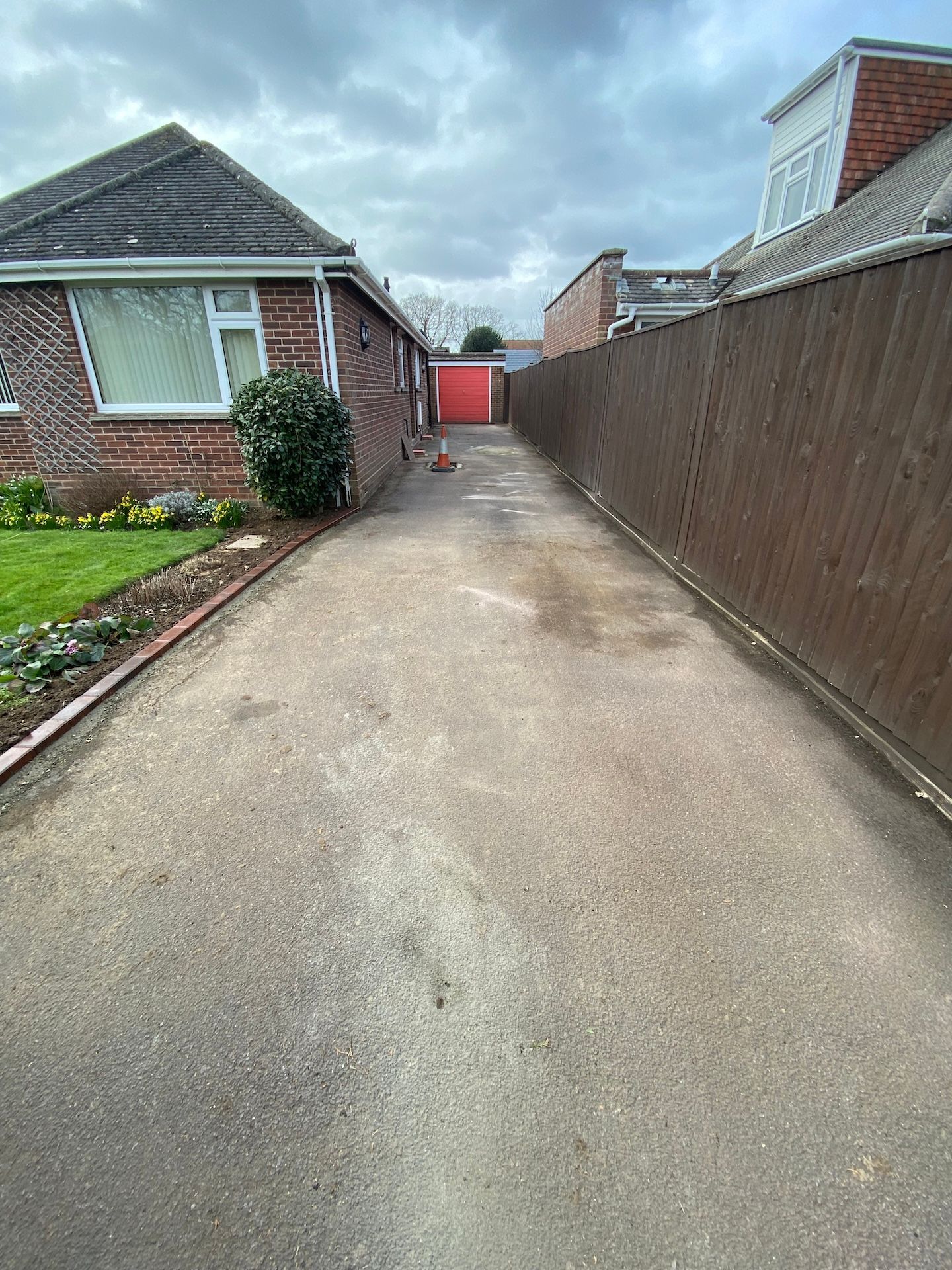 A long driveway leading to a house with a wooden fence.