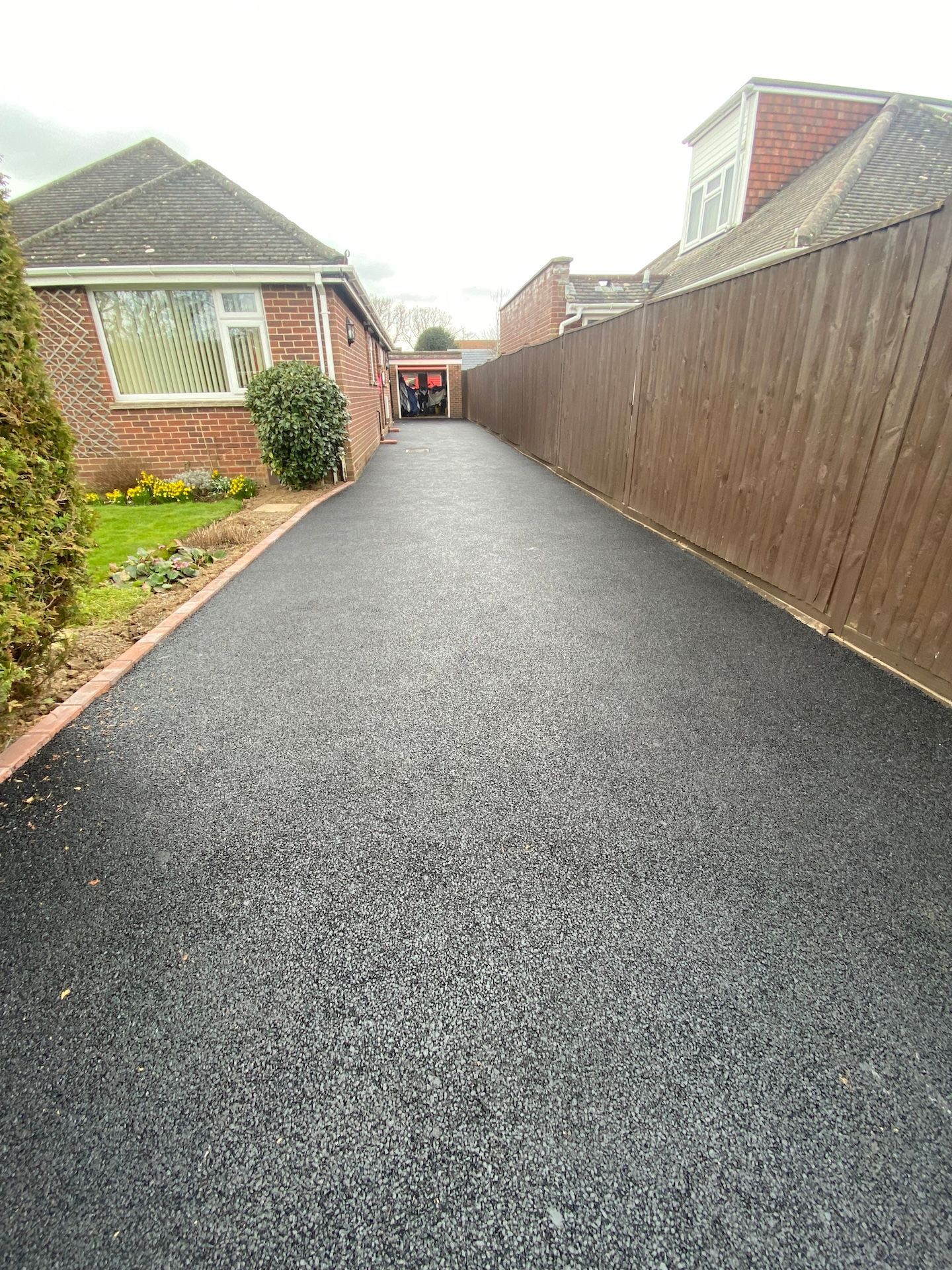 A driveway leading to a house with a wooden fence.