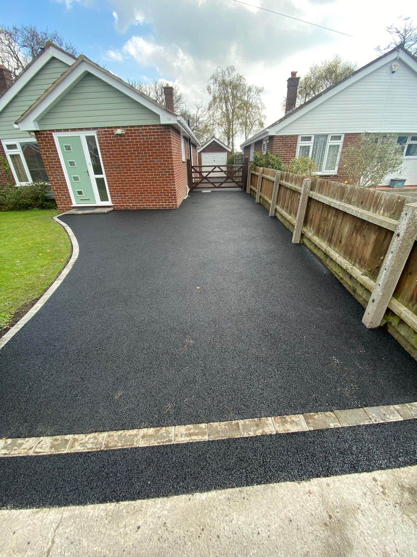 A driveway leading to a house with a wooden fence.