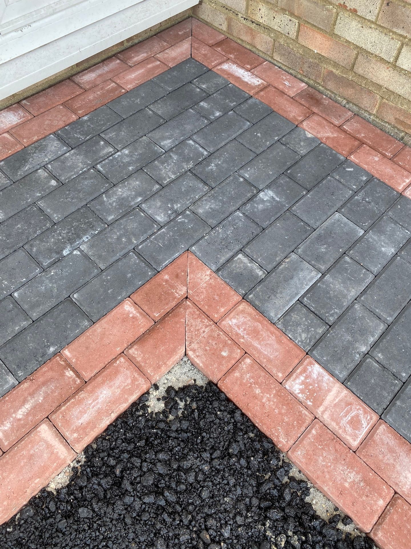 A close up of a brick walkway with a brick wall in the background.