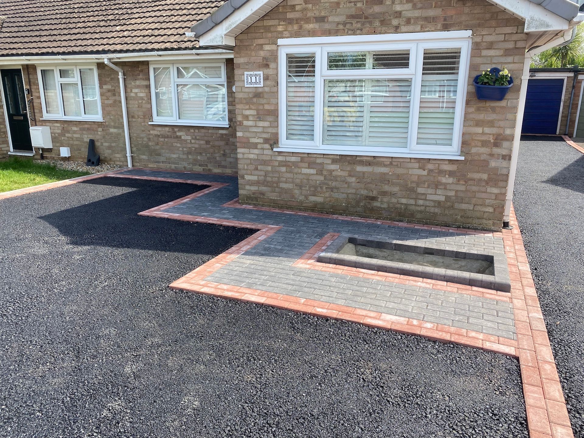 A brick house with a gravel driveway in front of it.