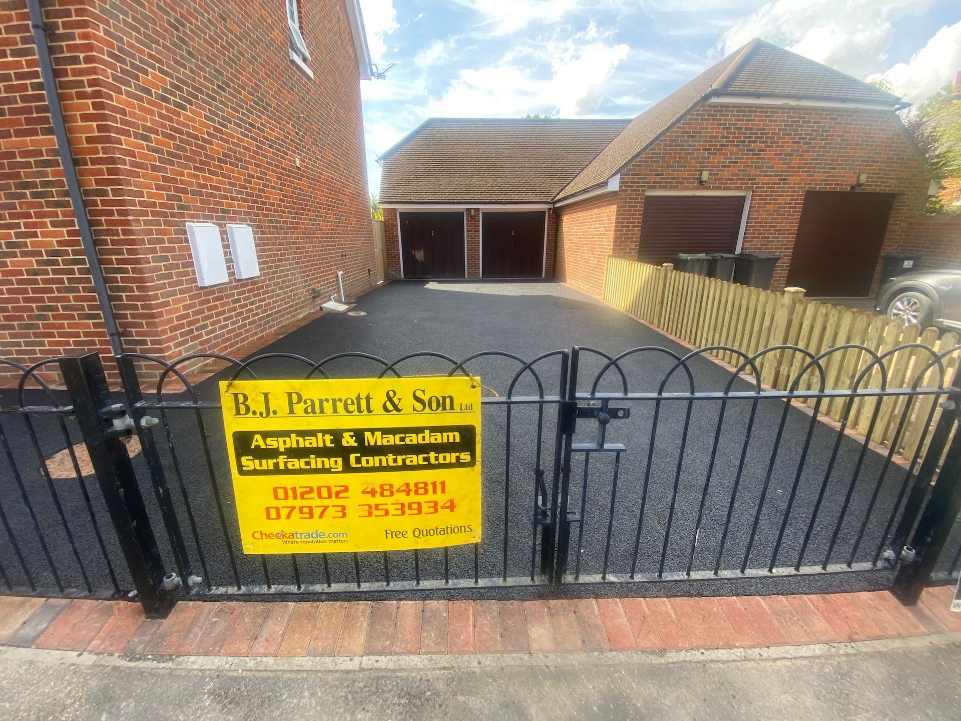 A yellow sign is hanging on a gate in front of a house.