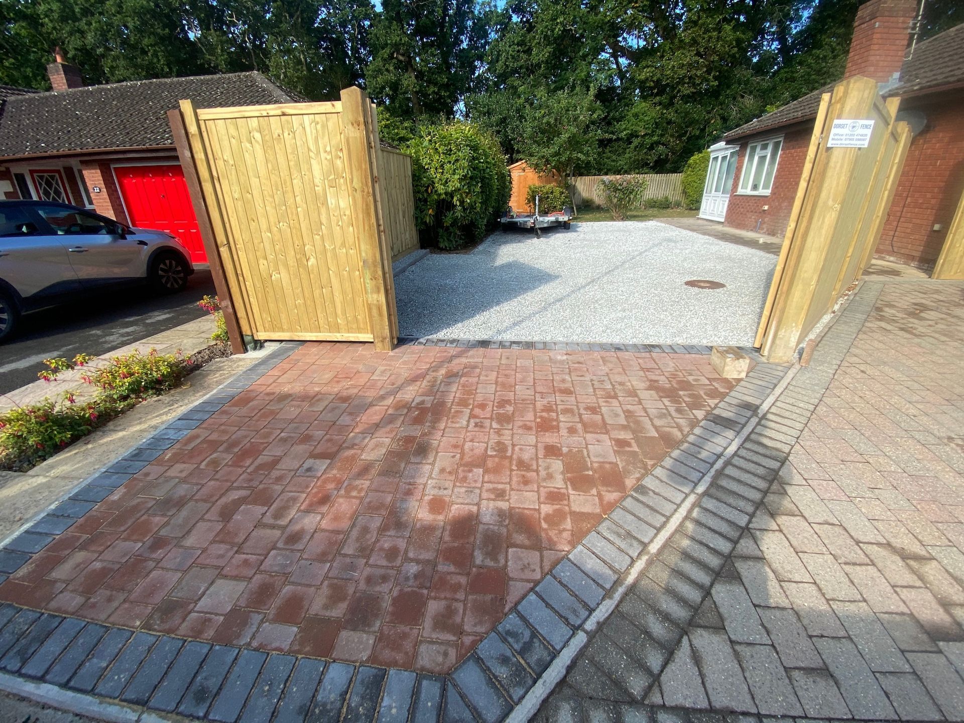 A car is parked in a driveway next to a wooden gate.