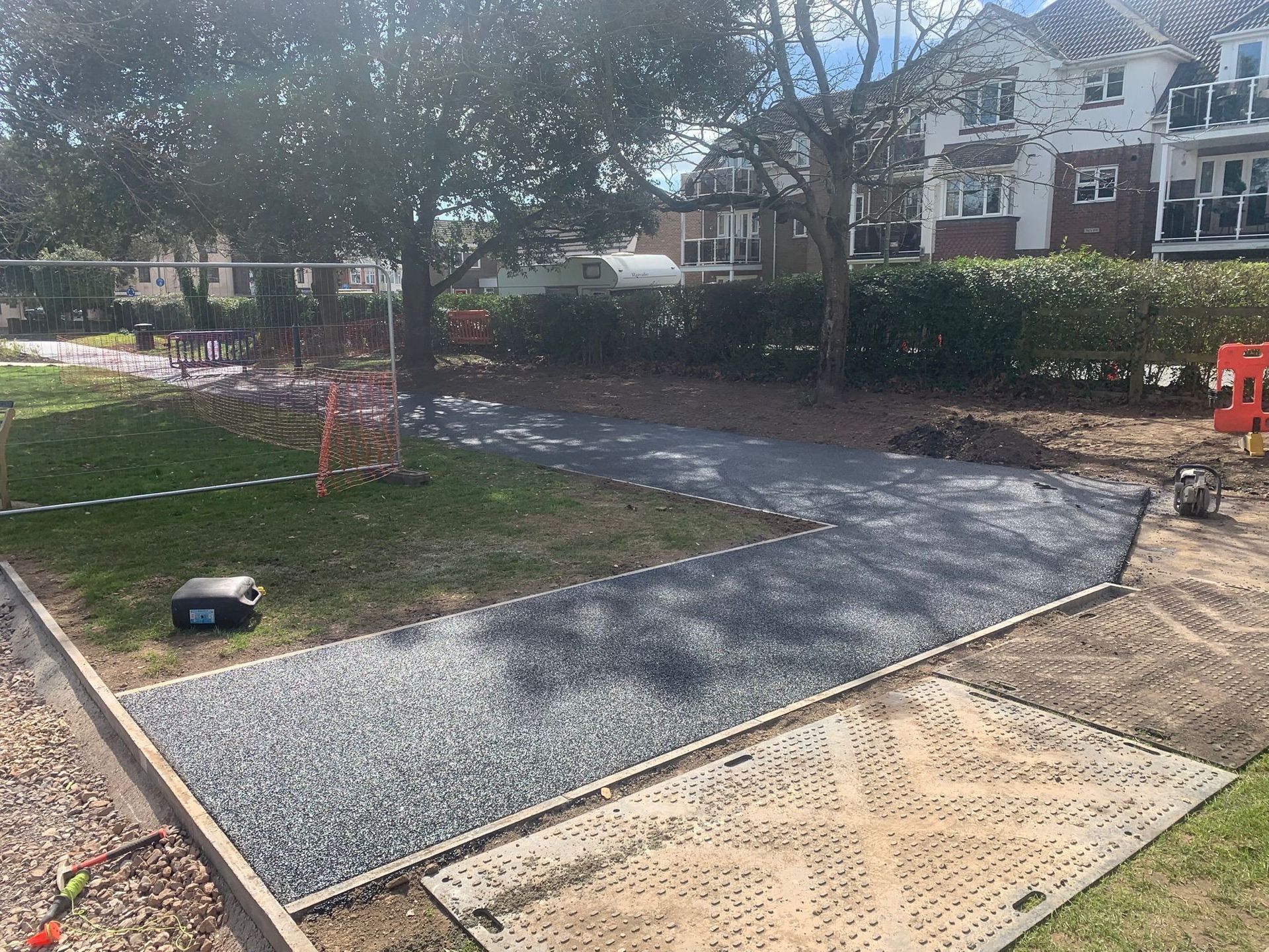 A gravel driveway is being built in a yard in front of a house.