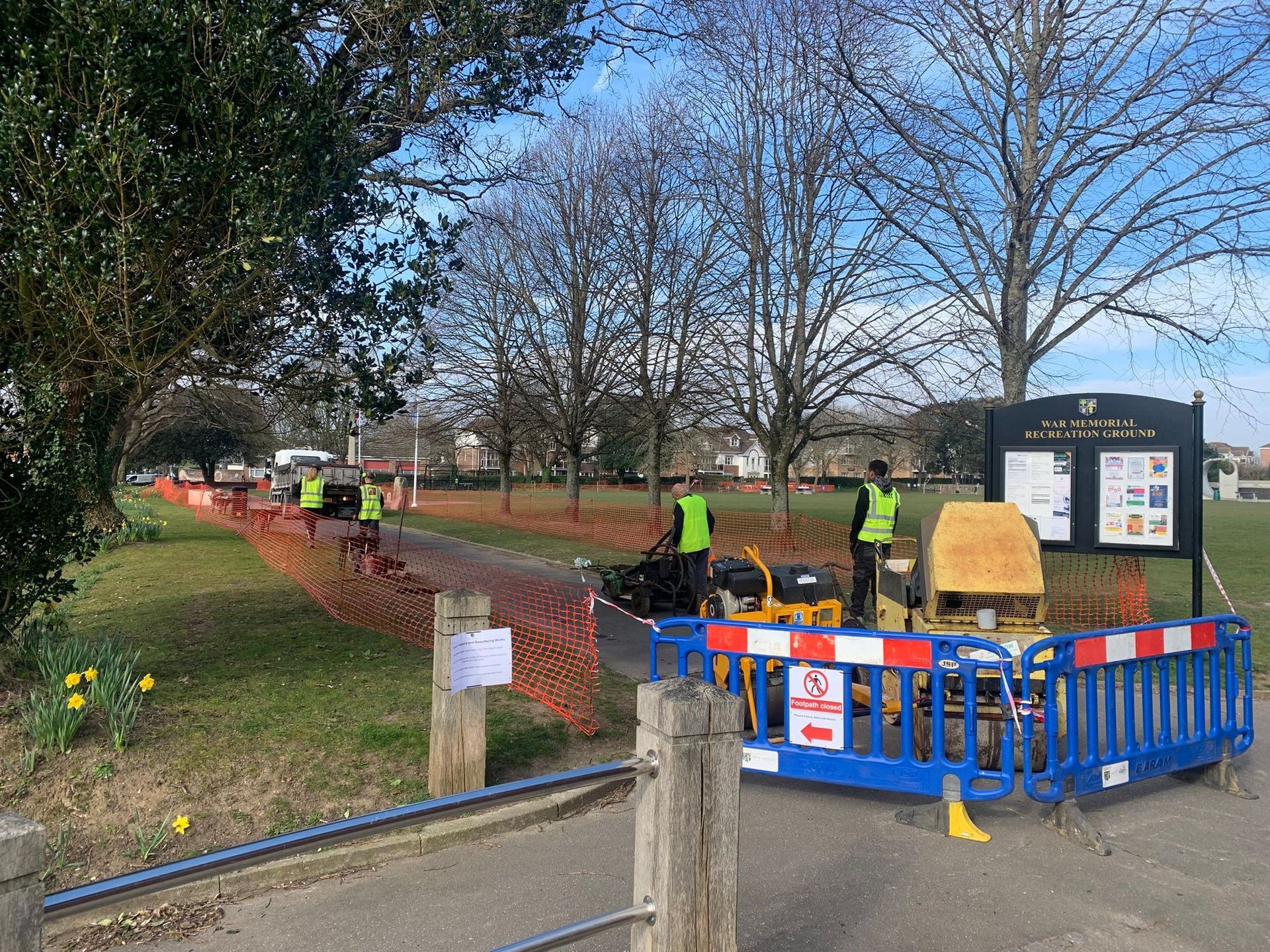 A group of people are working on a fence in a park.