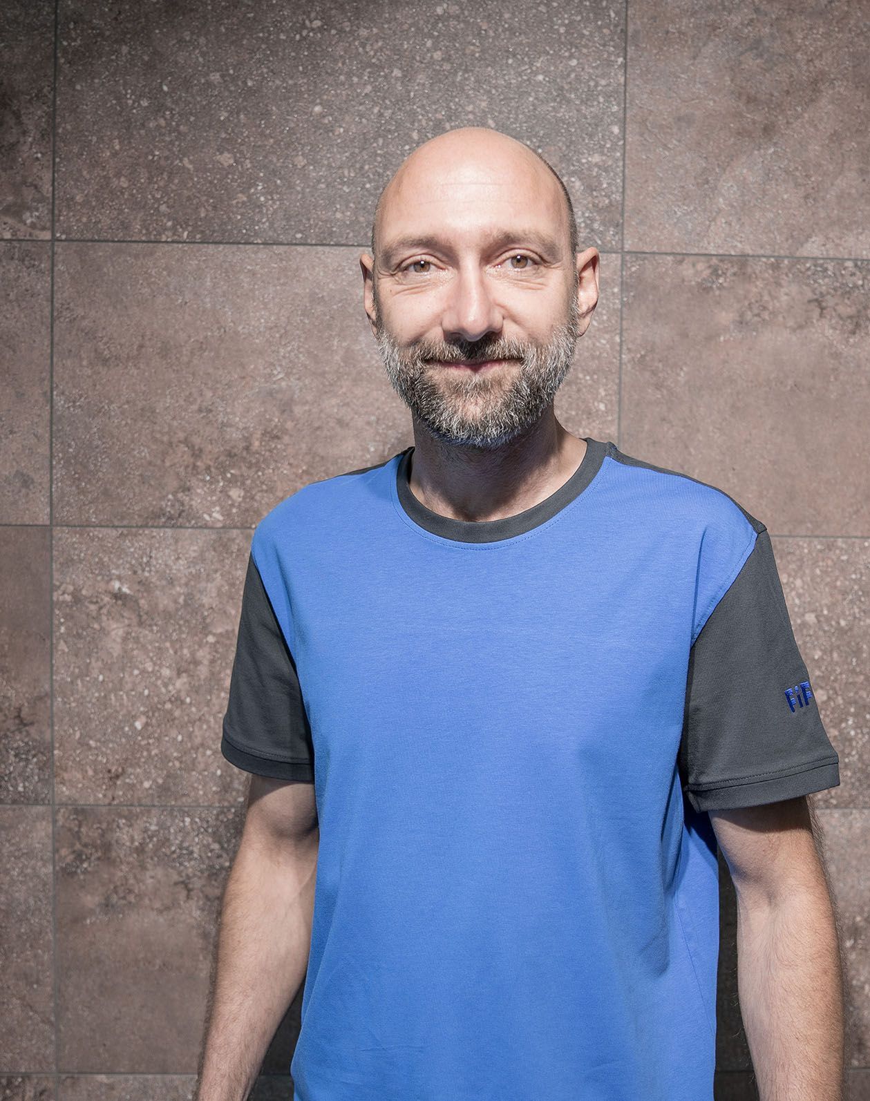 Das Portrait eines Mitarbeiters mit einem blauen T-Shirt