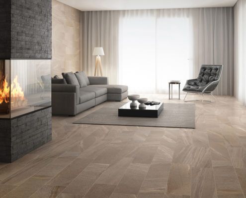 Ein Wohnzimmer mit Fliesenboden, Couch, Sessel, Tisch und Kamin.