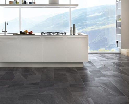 Ein Wohnzimmer mit Fliesenboden, Couch, Sessel, Tisch und Kamin.