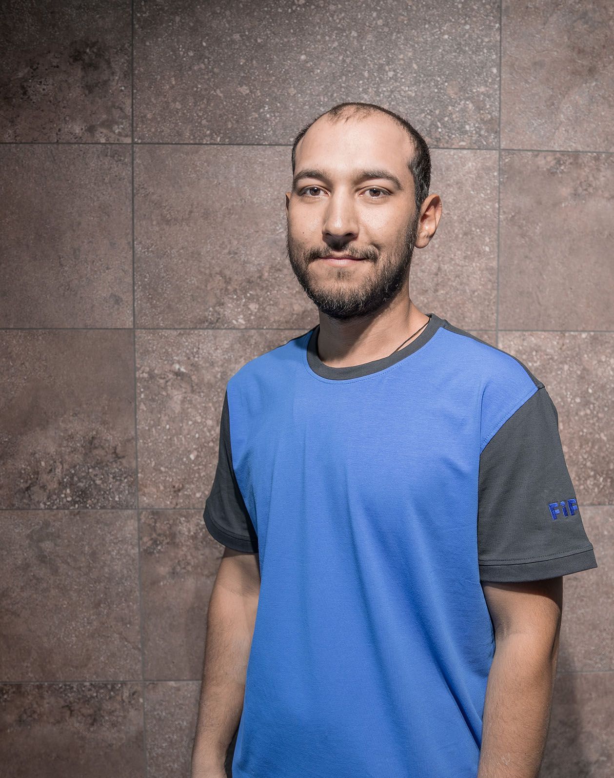 Das Portrait eines Mitarbeiters Heshmat Mohammadi mit einem blauen T-Shirt